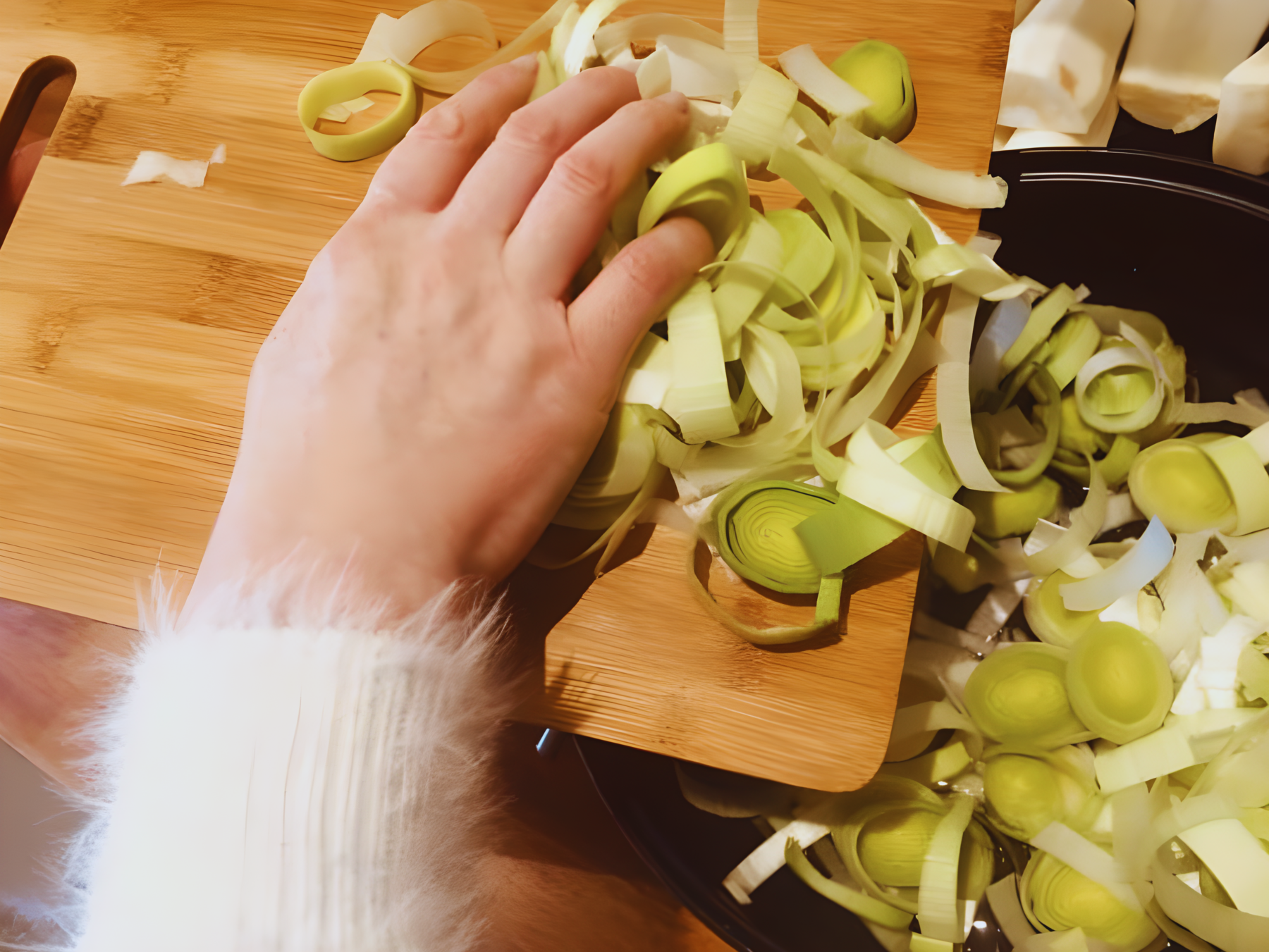 Pro Chefly Damascus chef knife cutting fresh leeks on wooden board.