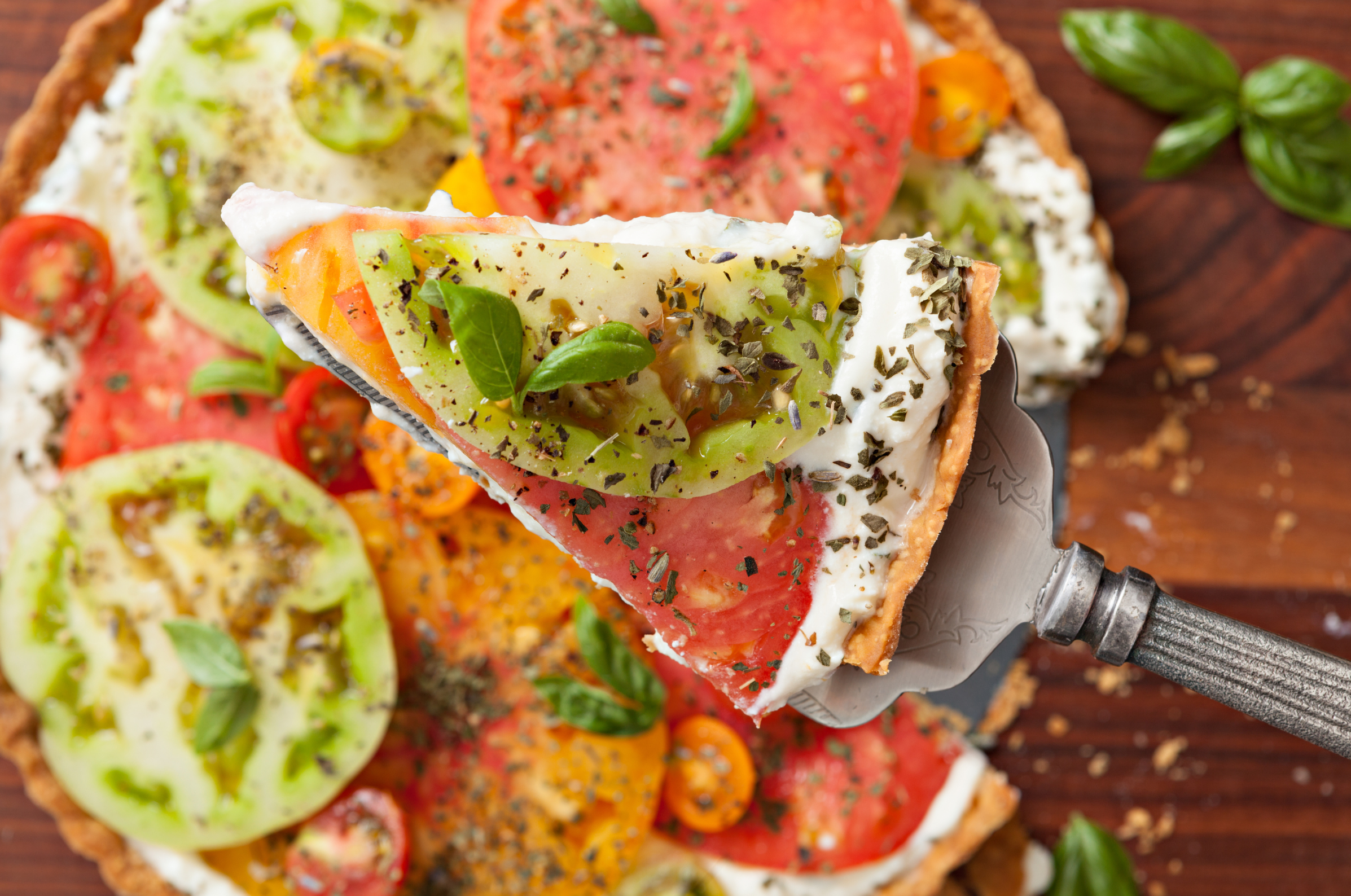 Image of Pro Chefly heirloom tomato tart with whipped feta, fresh basil, and seasoned tomatoes on a flaky crust.