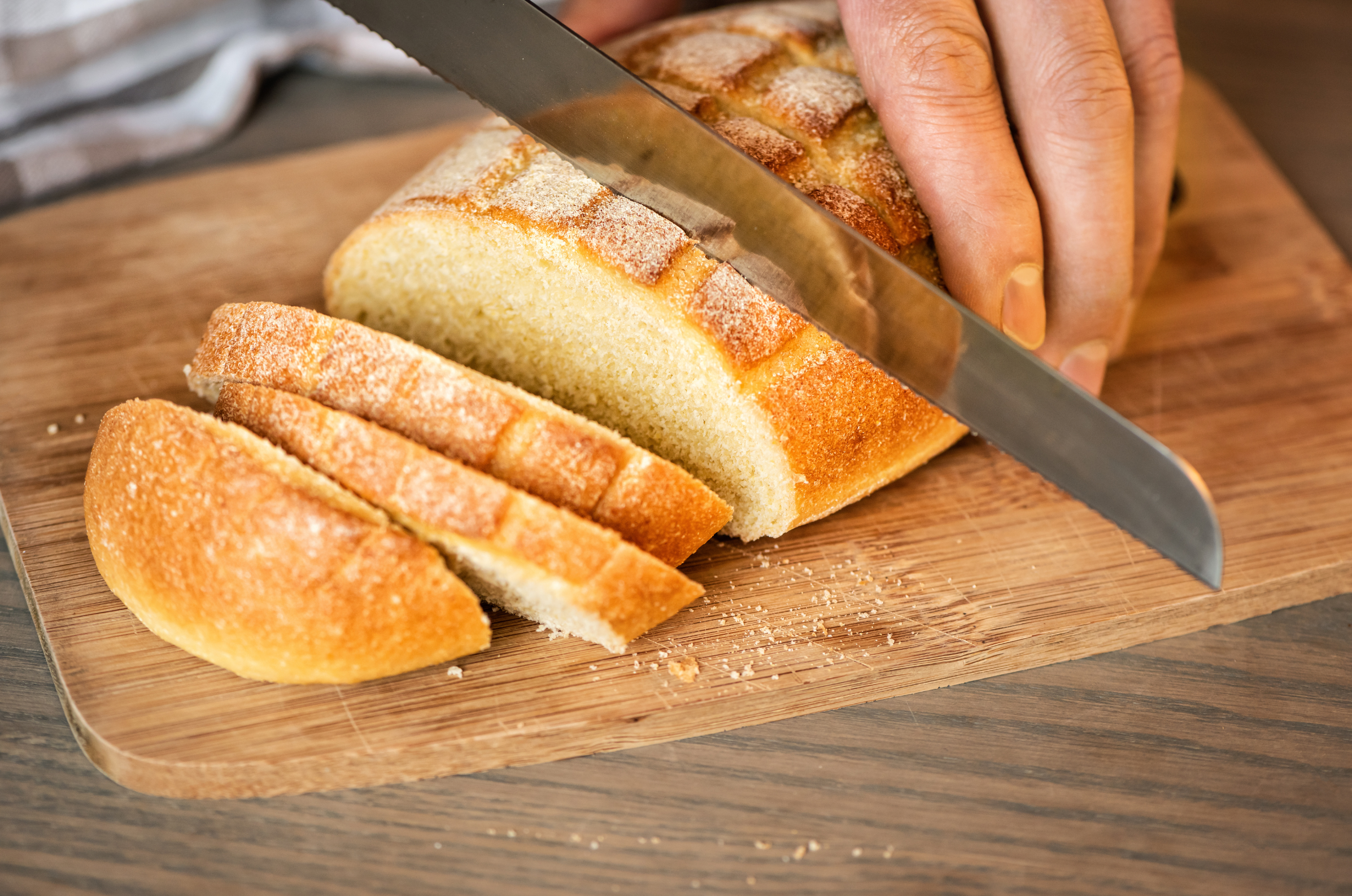 Image of Pro Chefly bread knife slicing a fresh artisan loaf on a wooden cutting board.