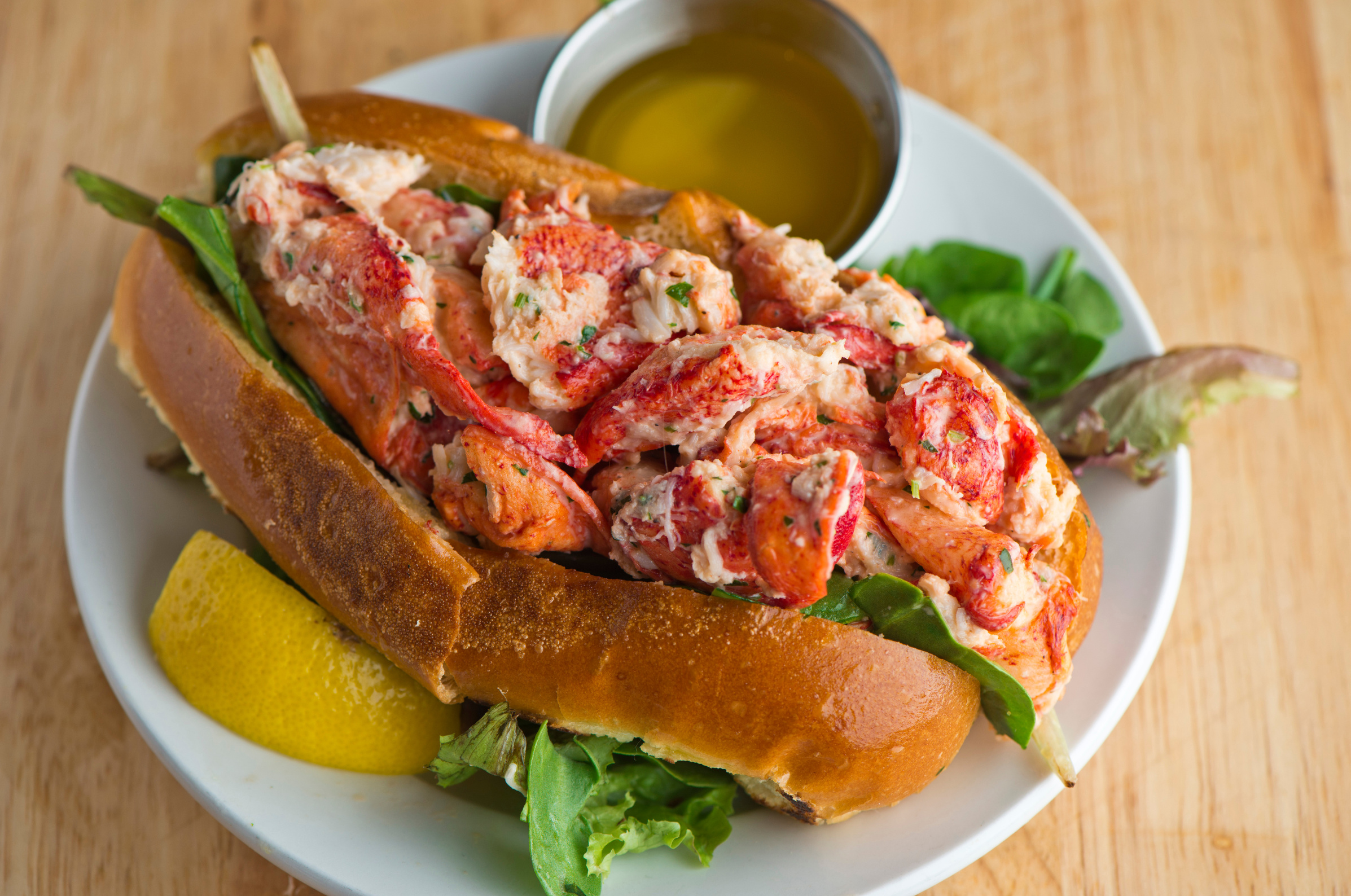 Image of Pro Chefly lobster roll packed with tender lobster meat, fresh greens, and a lemon wedge.