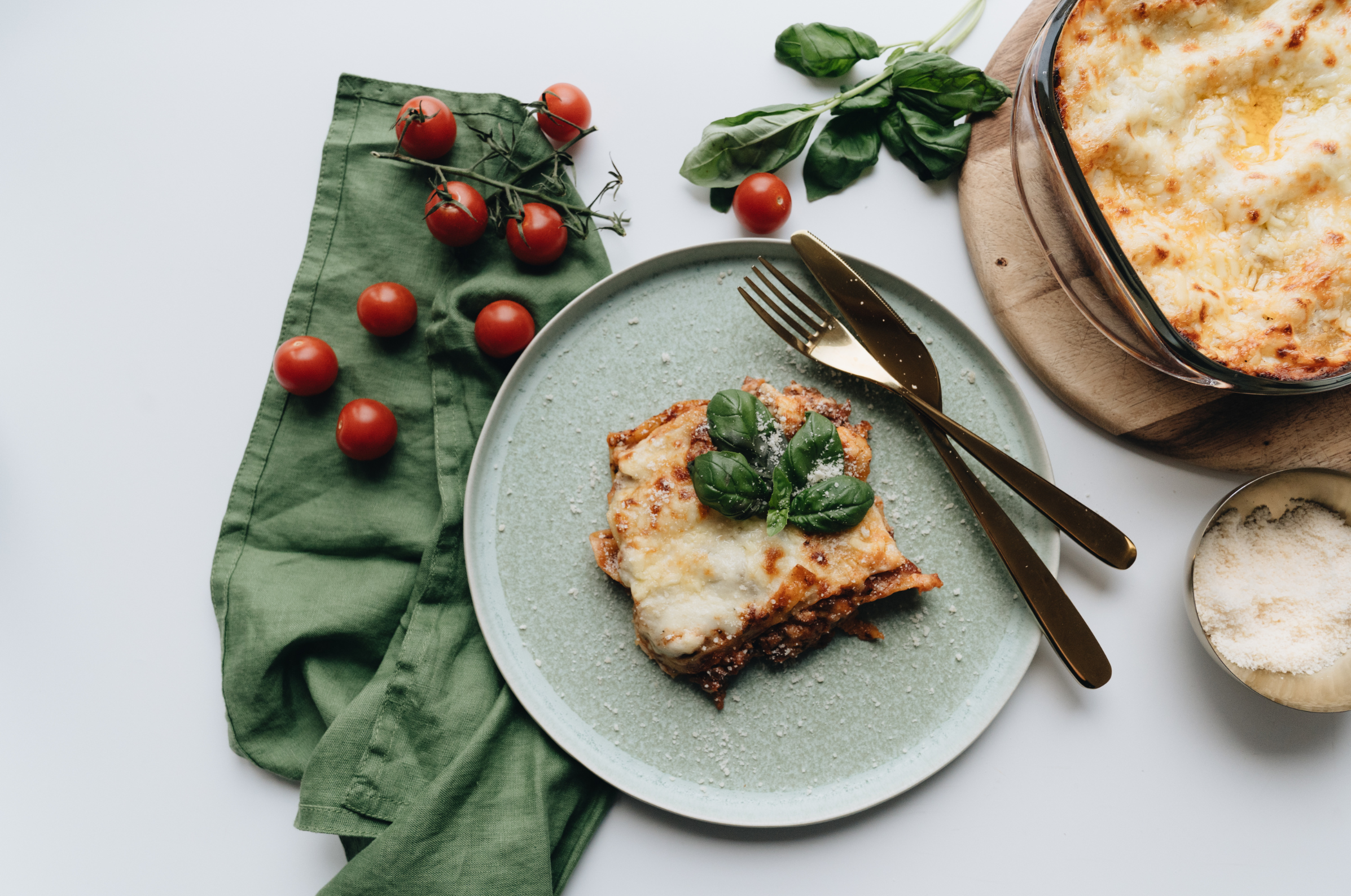 Image of Pro Chefly homemade lasagna plated with fresh basil and cherry tomatoes, highlighting artisanal cooking, comfort food craftsmanship, and elevated home kitchen style.
