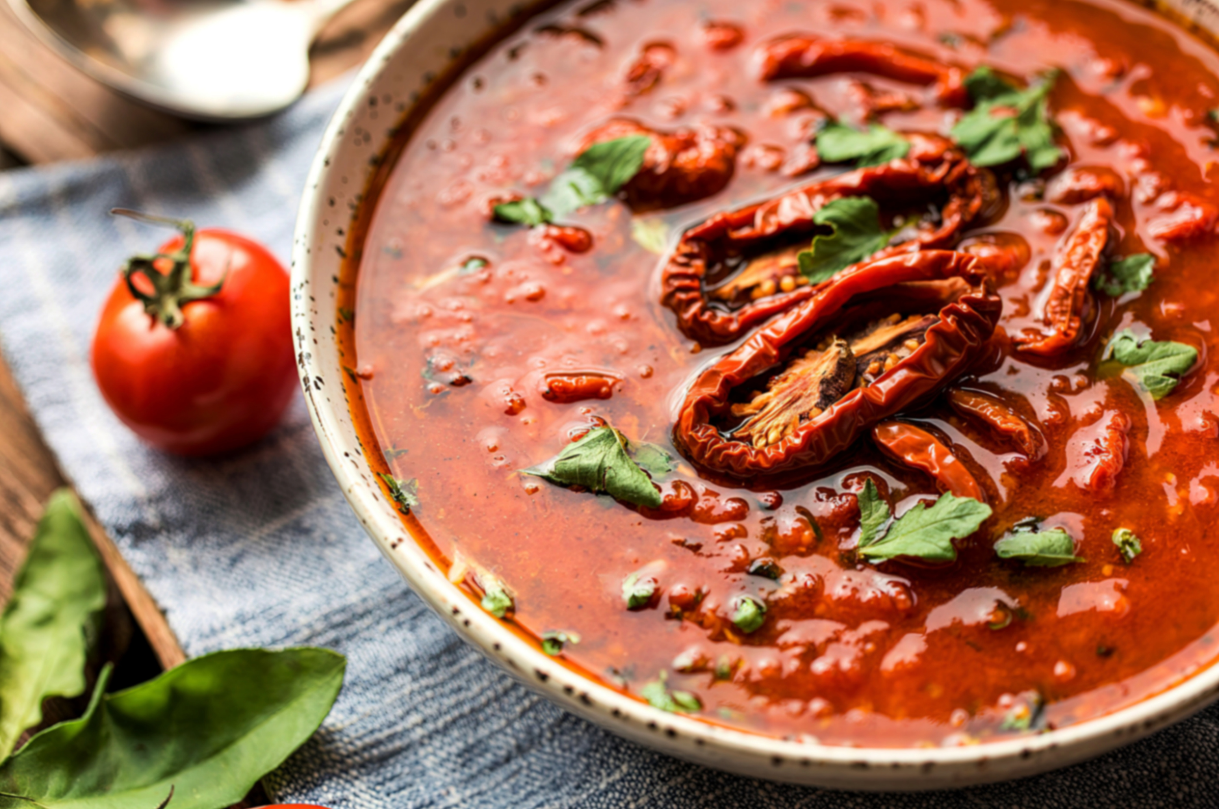 Image of Pro Chefly Nigerian pepper sauce in a ceramic bowl, rich red pepper and tomato base topped with dried peppers and fresh herbs