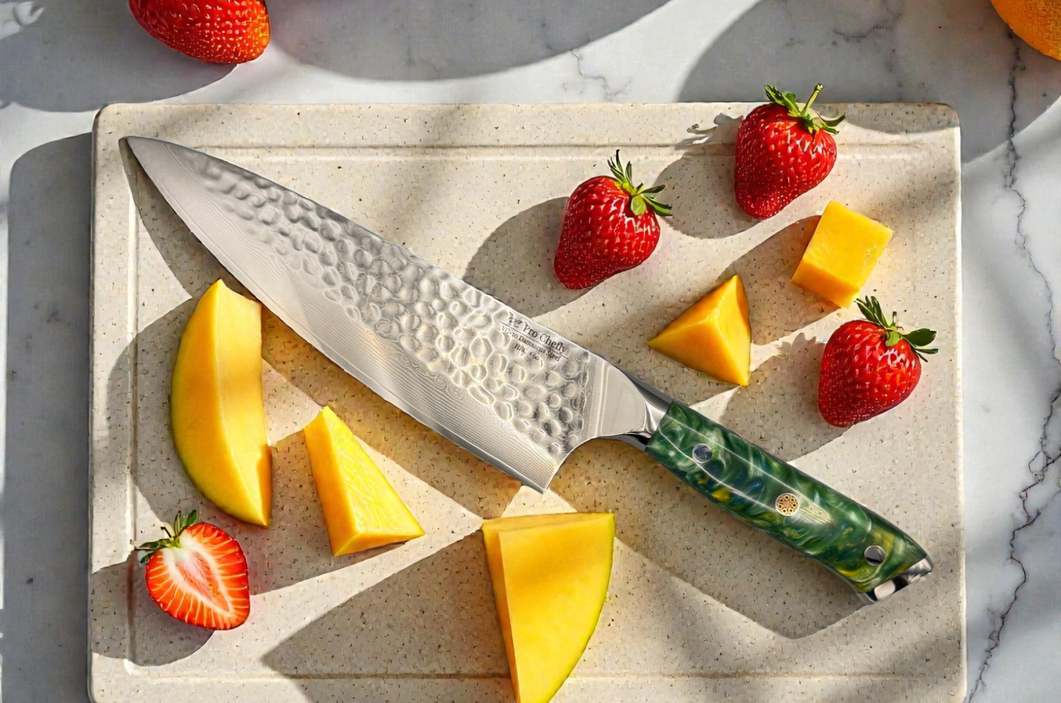 Image of Pro Chefly VG-10 Damascus santoku knife with hammered blade and green resin handle slicing fresh strawberries and mango on a stone cutting board.