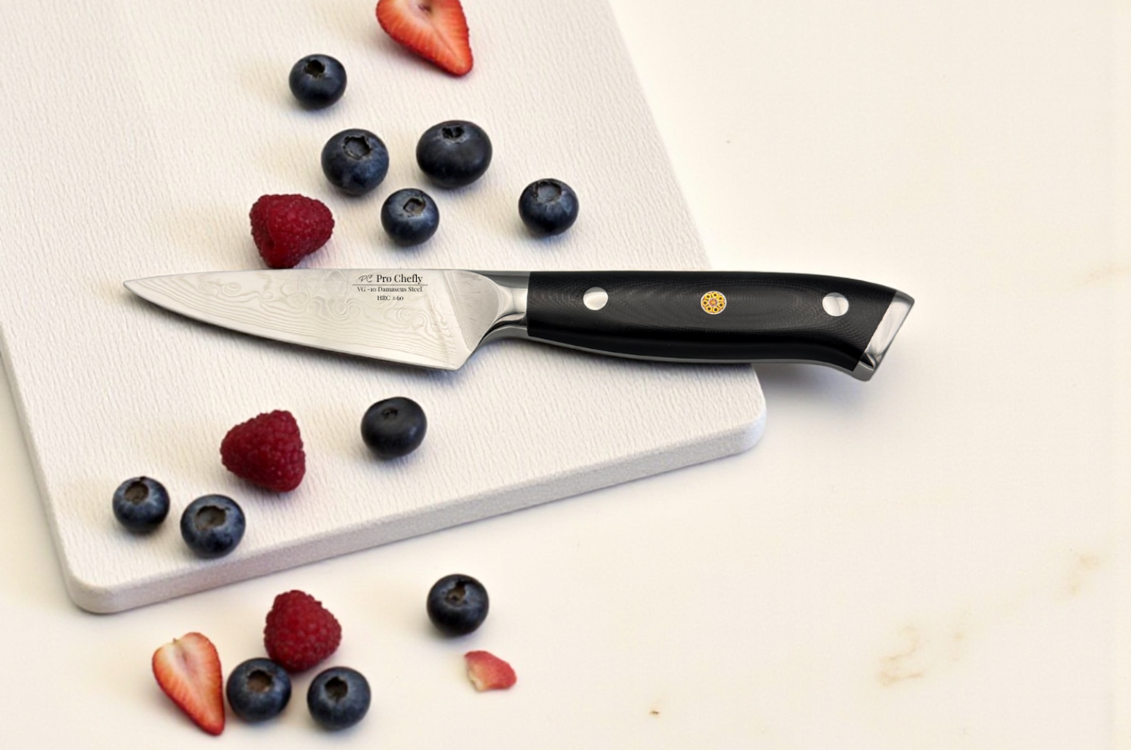 Image of Pro Chefly VG-10 Damascus paring knife with black handle resting on a white cutting board, styled with fresh strawberries, blueberries, and raspberries for precision fruit prep.