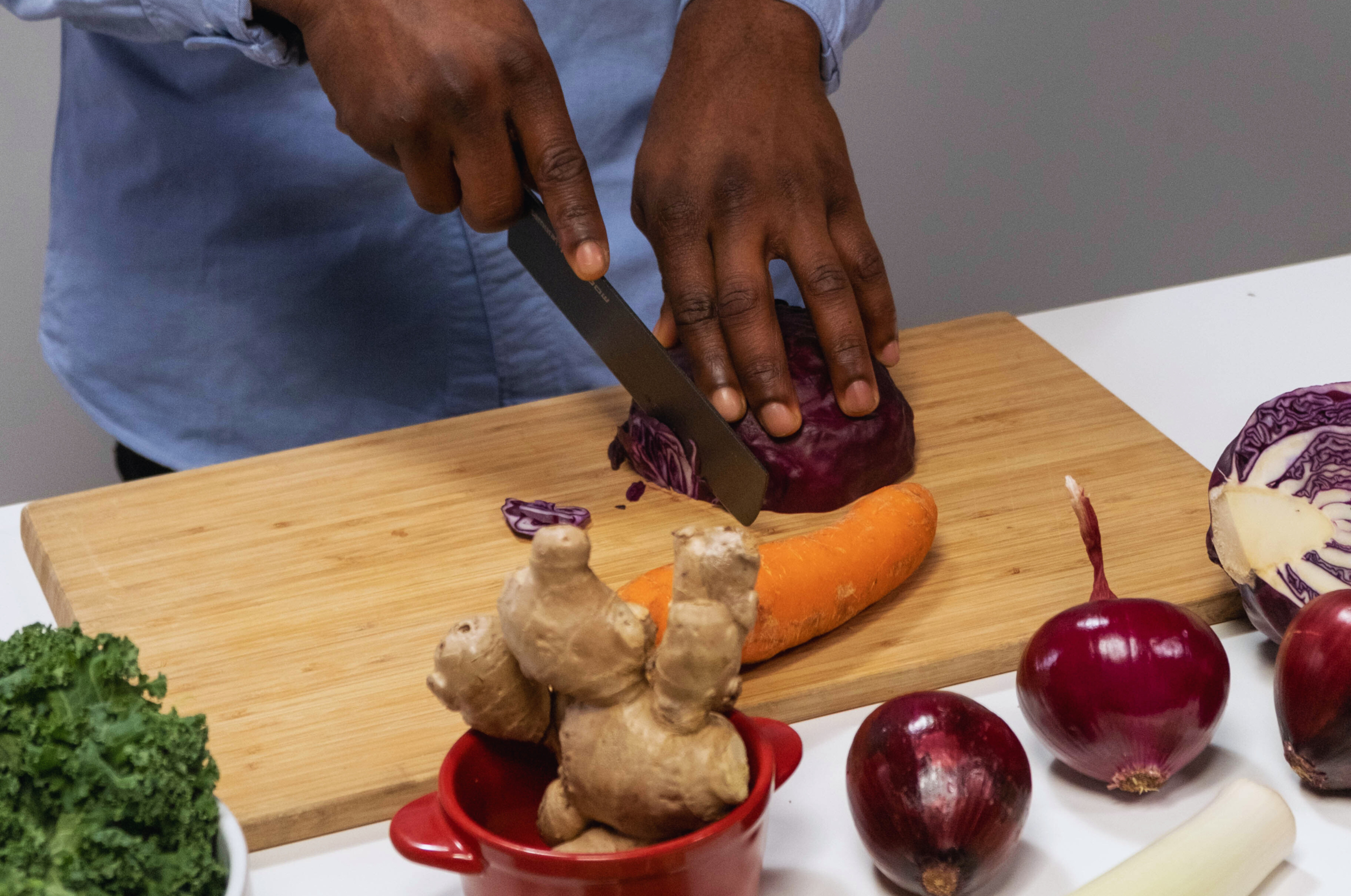 Image of Pro Chefly Japanese Damascus nakiri knife slicing red cabbage on a wooden cutting board, highlighting clean cuts and precise vegetable prep.