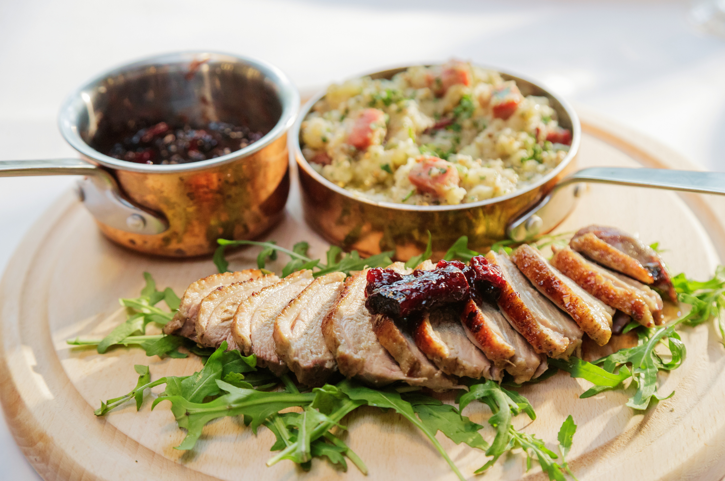 Image of Pro Chefly seared duck breast sliced and served over arugula with cherry gastrique and a side of quinoa.