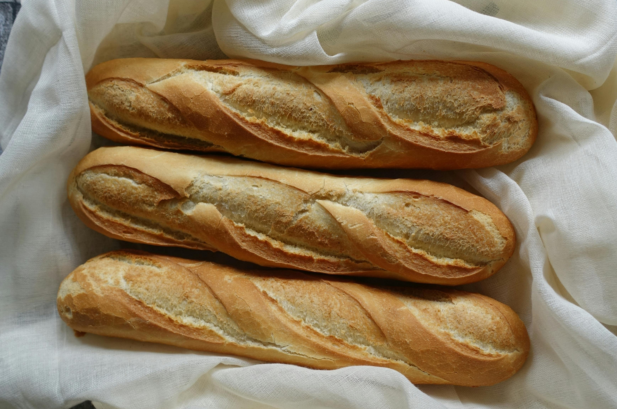 Image of Pro Chefly freshly baked golden baguettes with crisp crust and airy texture, styled on soft linen cloth with warm natural lighting, showcasing artisan bread craftsmanship