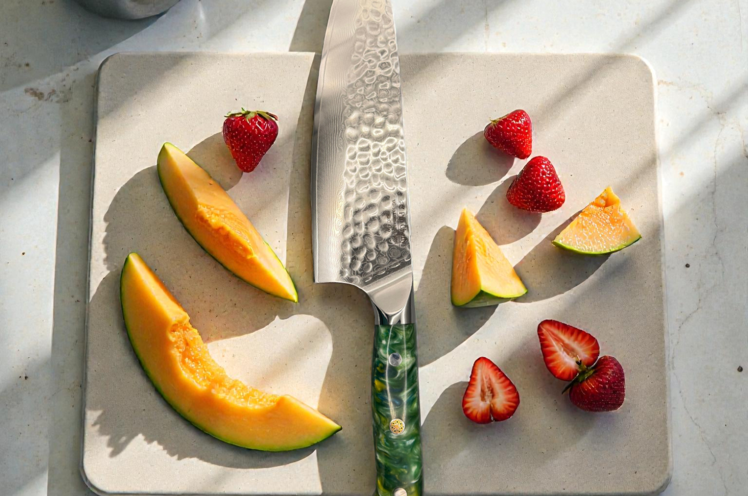 Image of Pro Chefly Damascus chef knife on a stone cutting board with sliced cantaloupe and strawberries, showing clean cuts and Japanese knife craftsmanship.