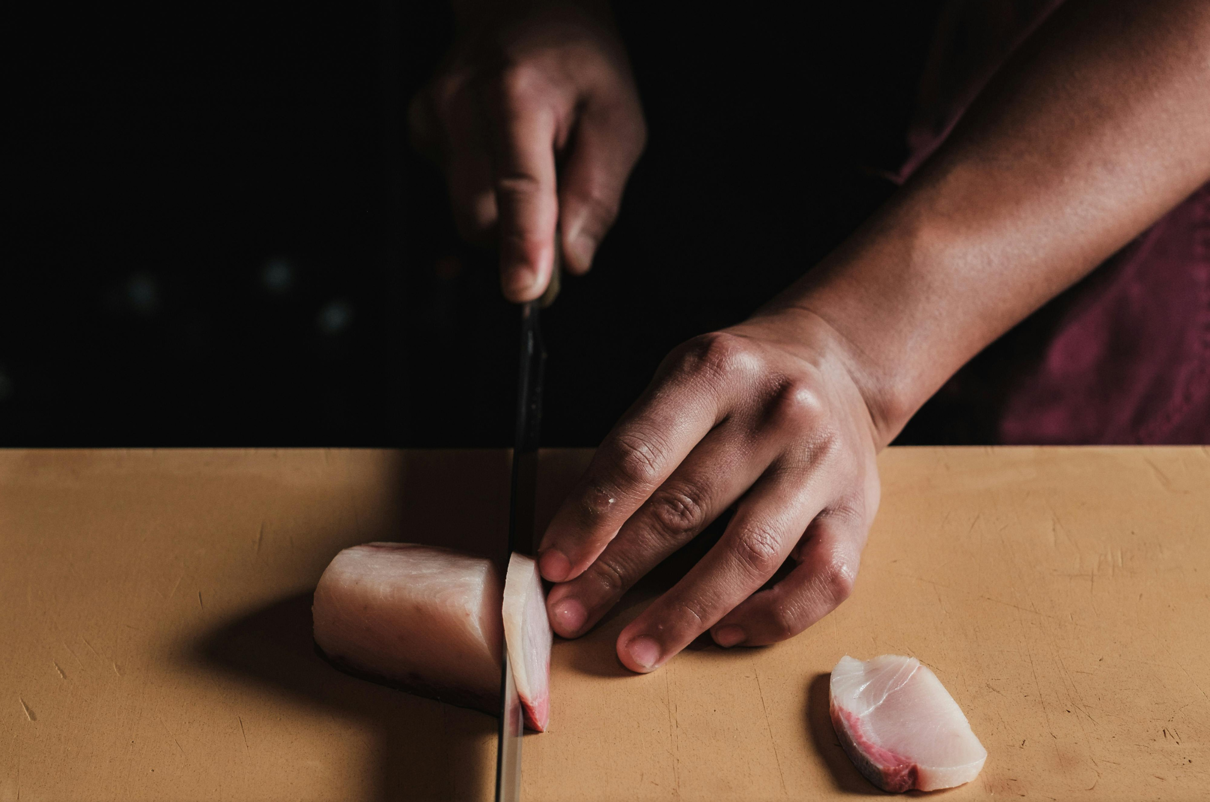 Image of Pro Chefly Japanese knives slicing fresh fish fillet on a wooden cutting board with precise, controlled technique.