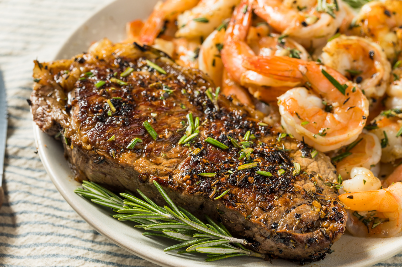 Image of Pro Chefly surf and turf featuring a perfectly seared steak with herb crust and garlic butter shrimp, plated with fresh rosemary and rich caramelized texture for a premium restaurant-style presentation