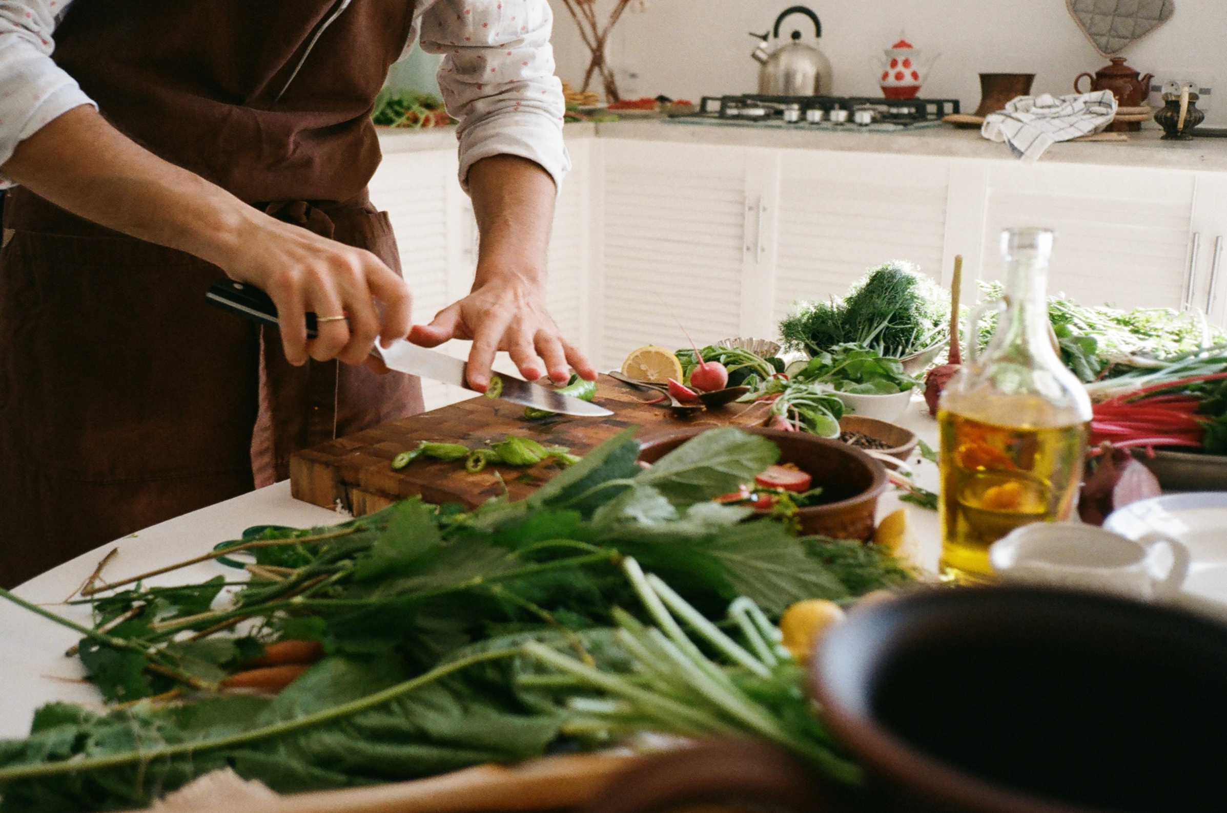 Image of Pro Chefly chef using Japanese knives to slice fresh herbs on a wooden cutting board during everyday kitchen prep.