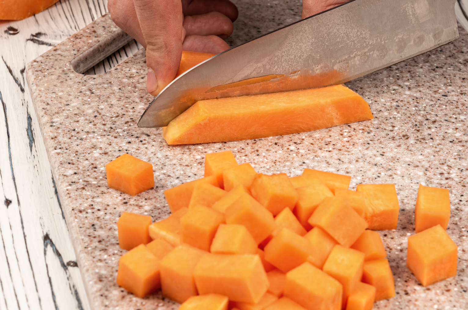 Image of Pro Chefly Damascus Japanese knife dicing fresh cantaloupe into uniform cubes, showcasing precision cuts, smooth blade control, and clean fruit prep on a cutting board