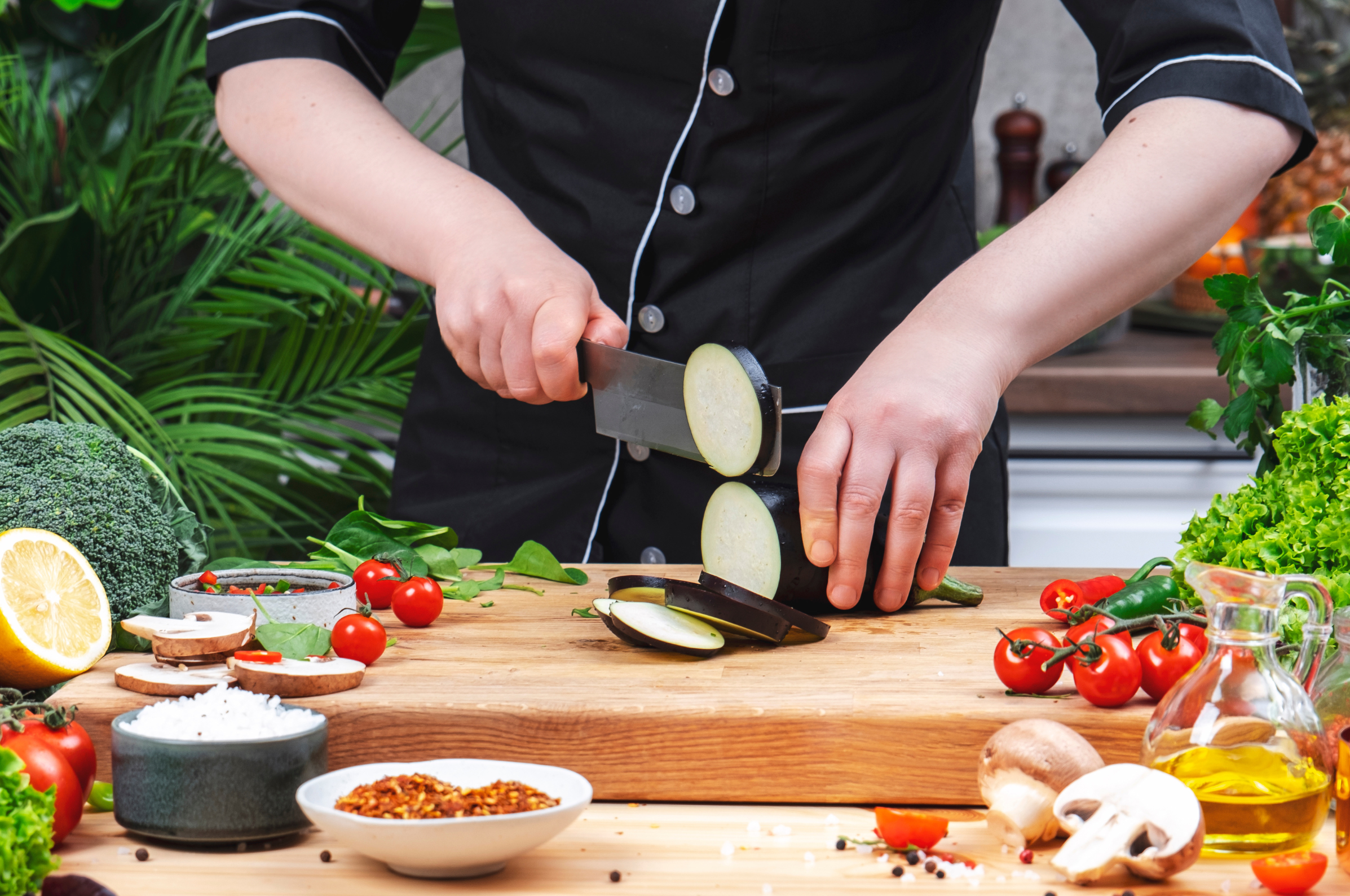 Image of Pro Chefly Japanese Damascus nakiri knife slicing eggplant on a wooden cutting board, highlighting controlled cuts, sharp blade performance, and professional vegetable prep.