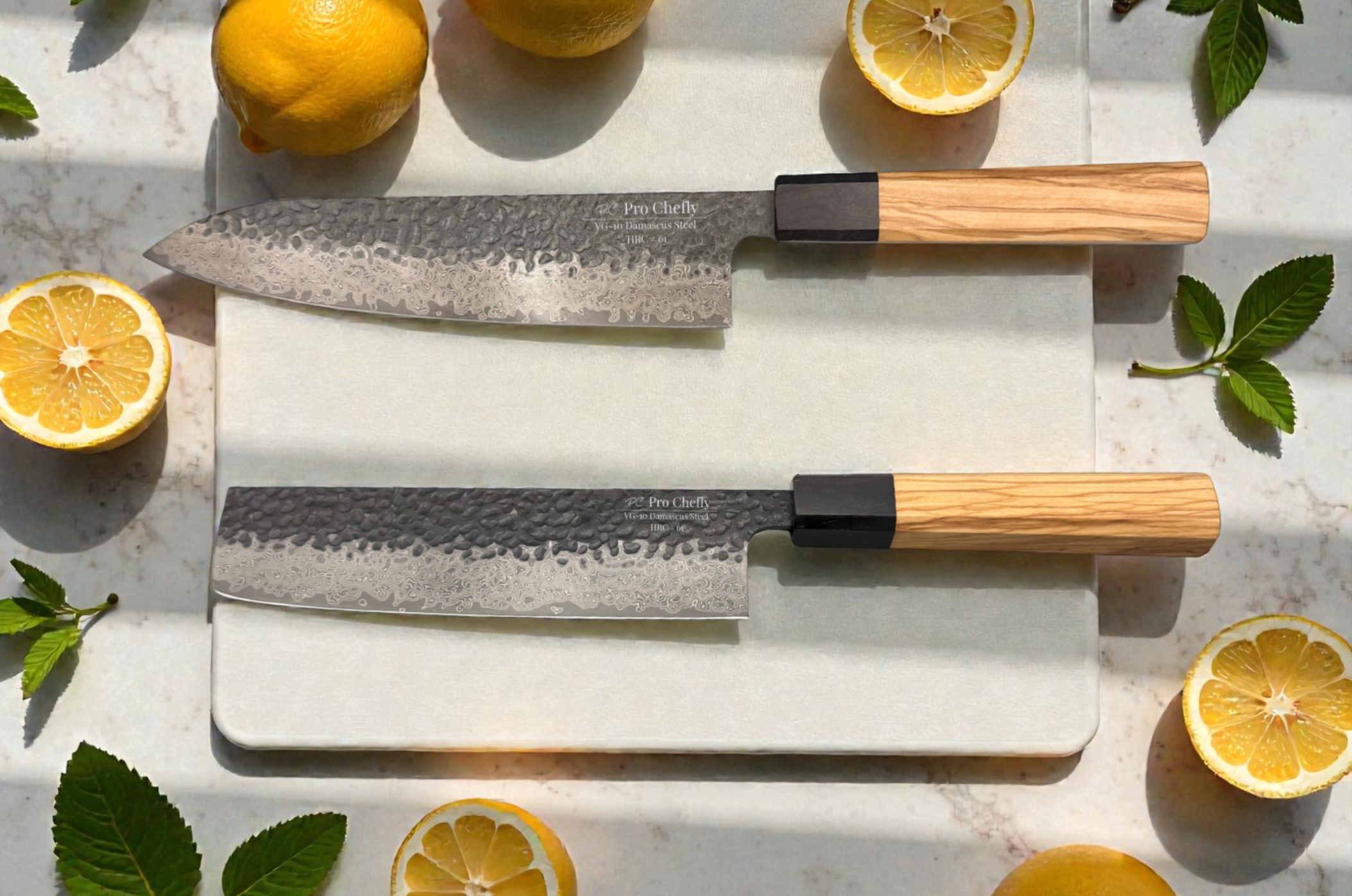 Image of Pro Chefly VG-10 Damascus chef knife and nakiri knife with hammered finish and light wood handles displayed on a marble board with fresh lemons and green leaves.