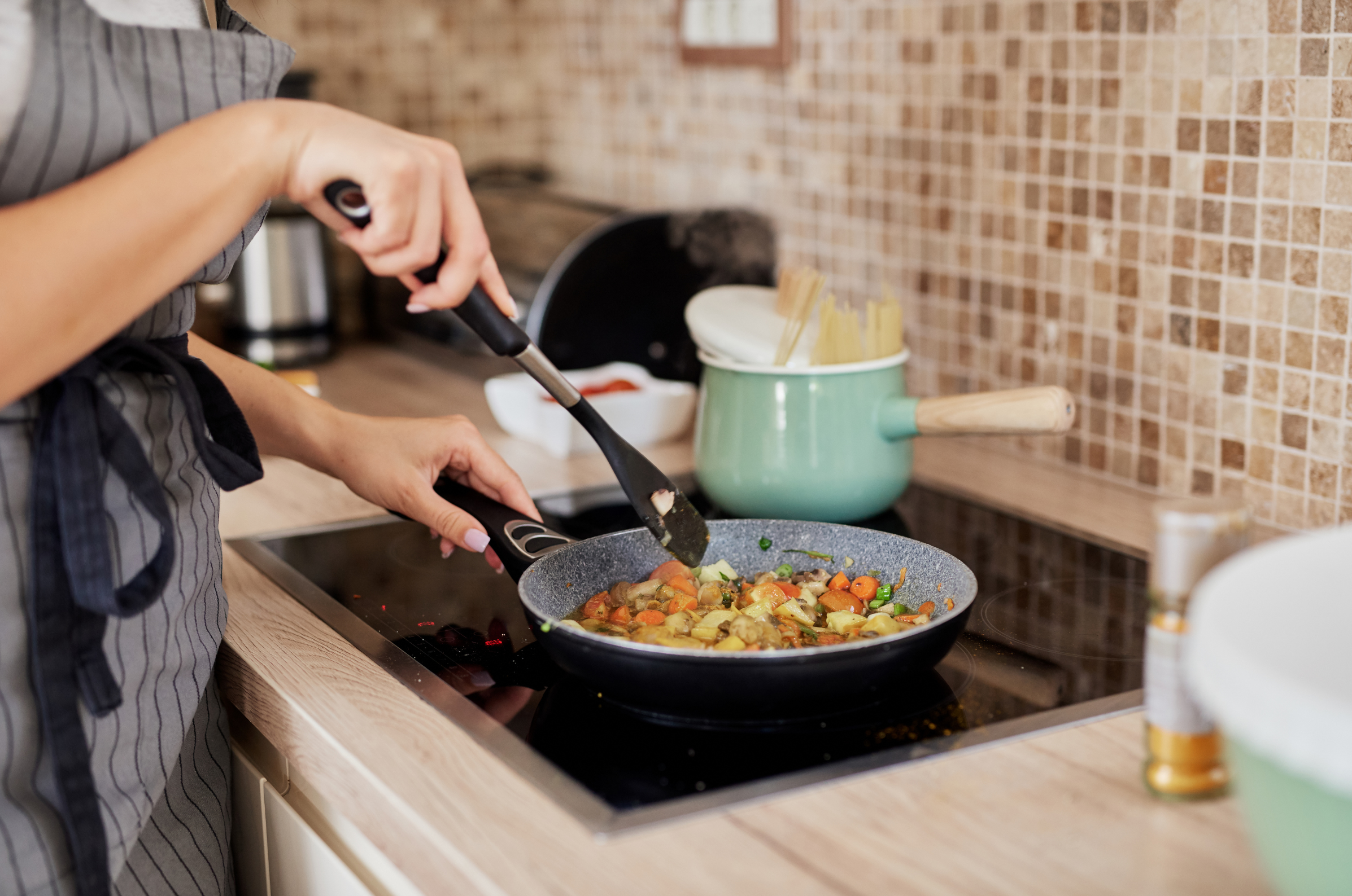 Image of Pro Chefly home cooking scene with sautéed vegetables in a skillet on a stovetop, chef stirring with a spatula in a modern kitchen setting.