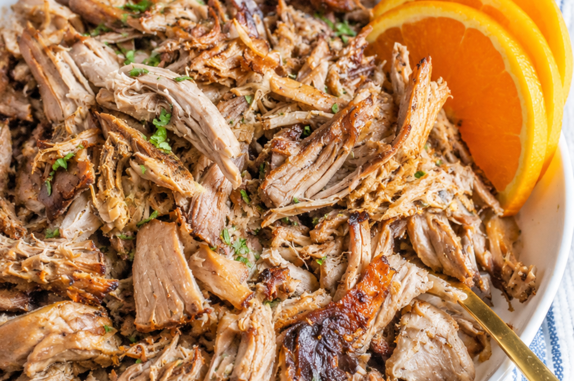 Image of Pro Chefly slow-roasted mojo pork shoulder, hand-pulled into tender citrus-marinated shreds and served with fresh orange slices for a flavorful Cuban-inspired meal.