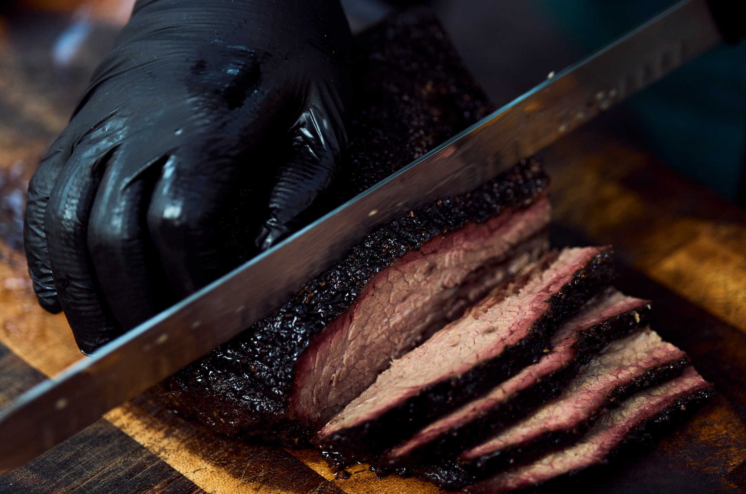 Image of Pro Chefly smoked beef brisket sliced on a wooden cutting board, showcasing a rich bark, tender interior, and expert barbecue technique.