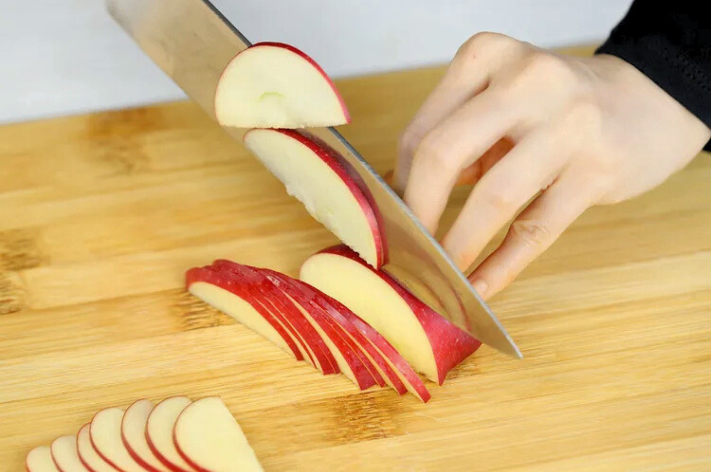 Image of Pro Chefly Japanese Aogami Blue #2 steel knife slicing a red apple on a wooden cutting board, showcasing clean cuts, sharp precision, and controlled everyday prep.
