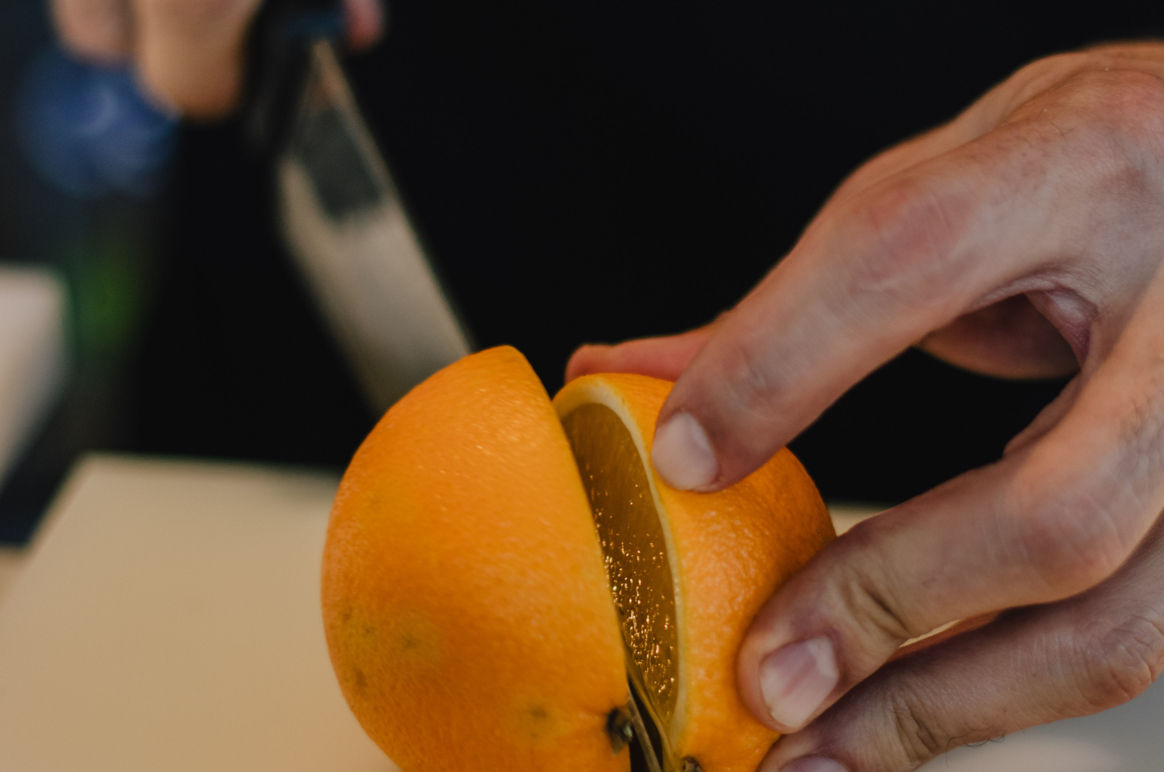 Image of Pro Chefly Damascus nakiri knife slicing a fresh orange, showcasing precision knife skills and effortless citrus preparation.