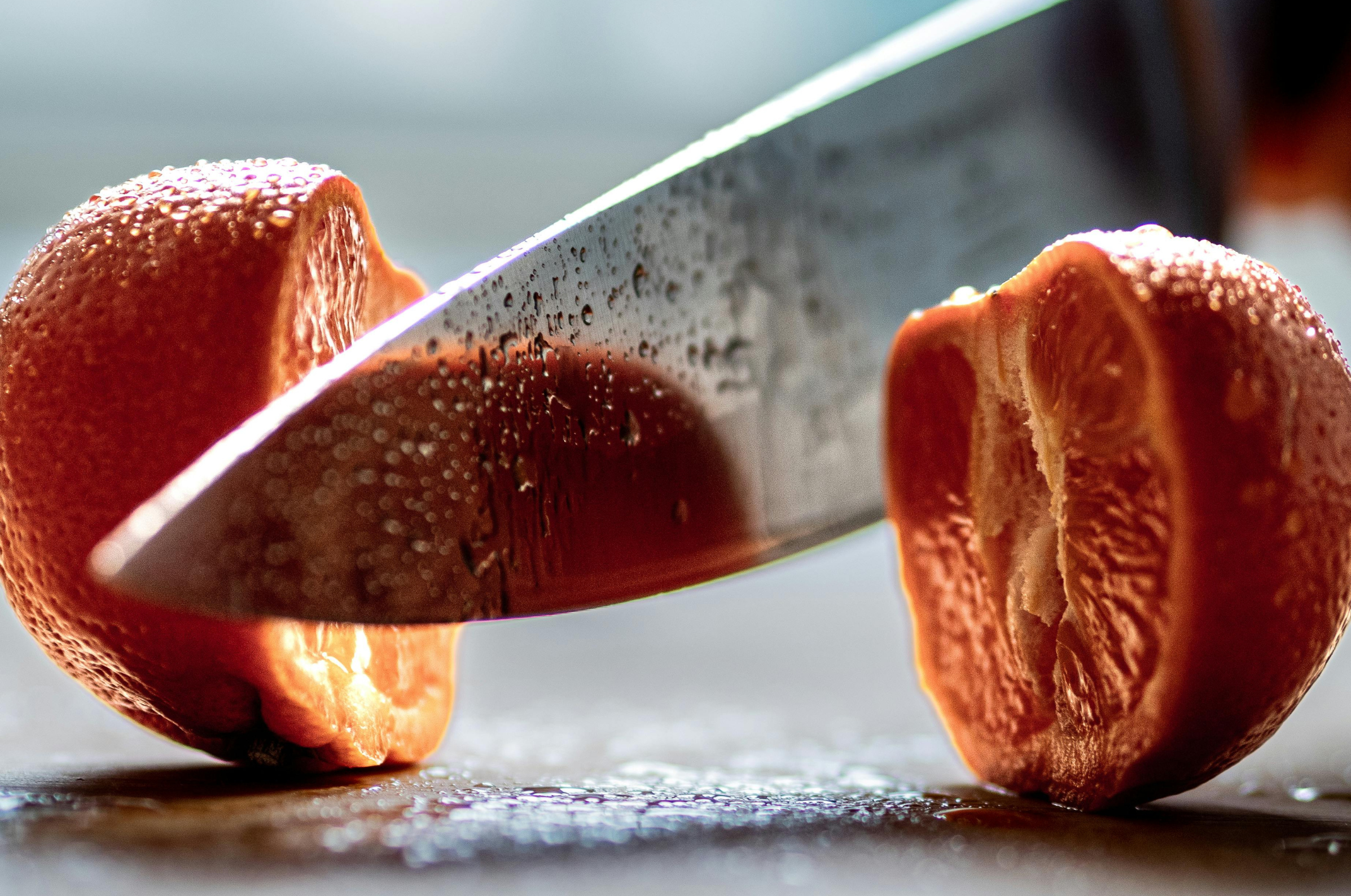 Image of Pro Chefly Damascus chef knife slicing a fresh tangerine in half, highlighting razor-sharp precision and clean, effortless cuts.