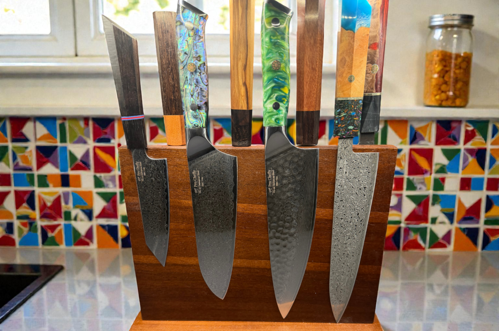 Image of Pro Chefly Damascus Japanese knife set on a wooden magnetic block, featuring patterned Damascus blades and artisan wood and resin handles in a modern kitchen.