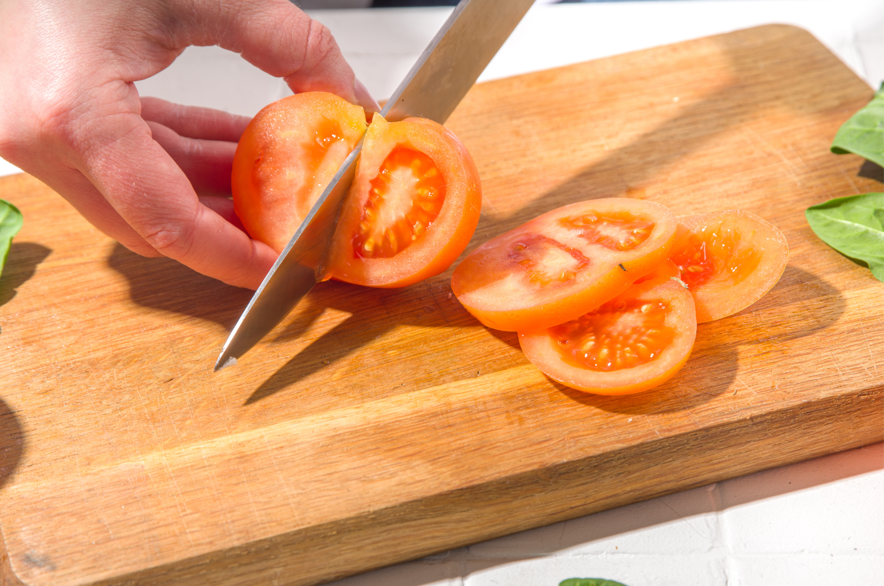 Image of Chef slicing ripe tomato on wooden cutting board with a sharp Japanese Damascus knife