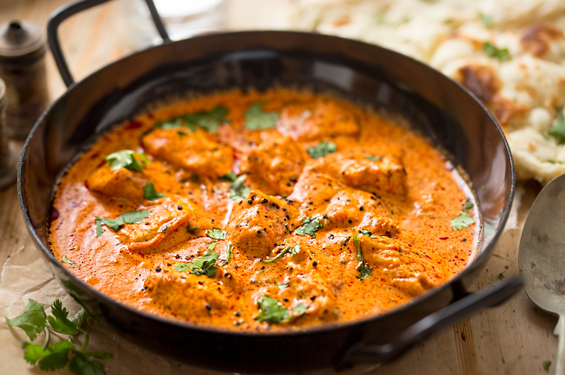 Image of Authentic Indian butter chicken served with basmati rice, naan, and raita in white bowls, garnished with fresh cilantro – Pro Chefly.