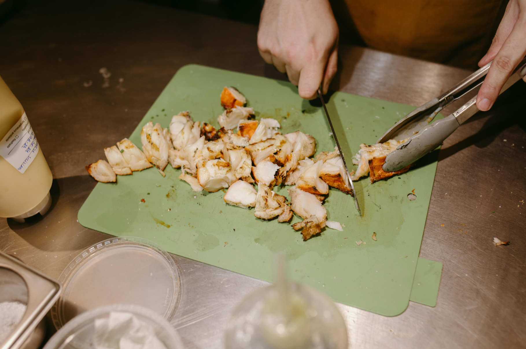 Grilled chicken being chopped into bite-sized pieces on a cutting board using a Pro Chefly chef knife for precise and efficient kitchen prep.