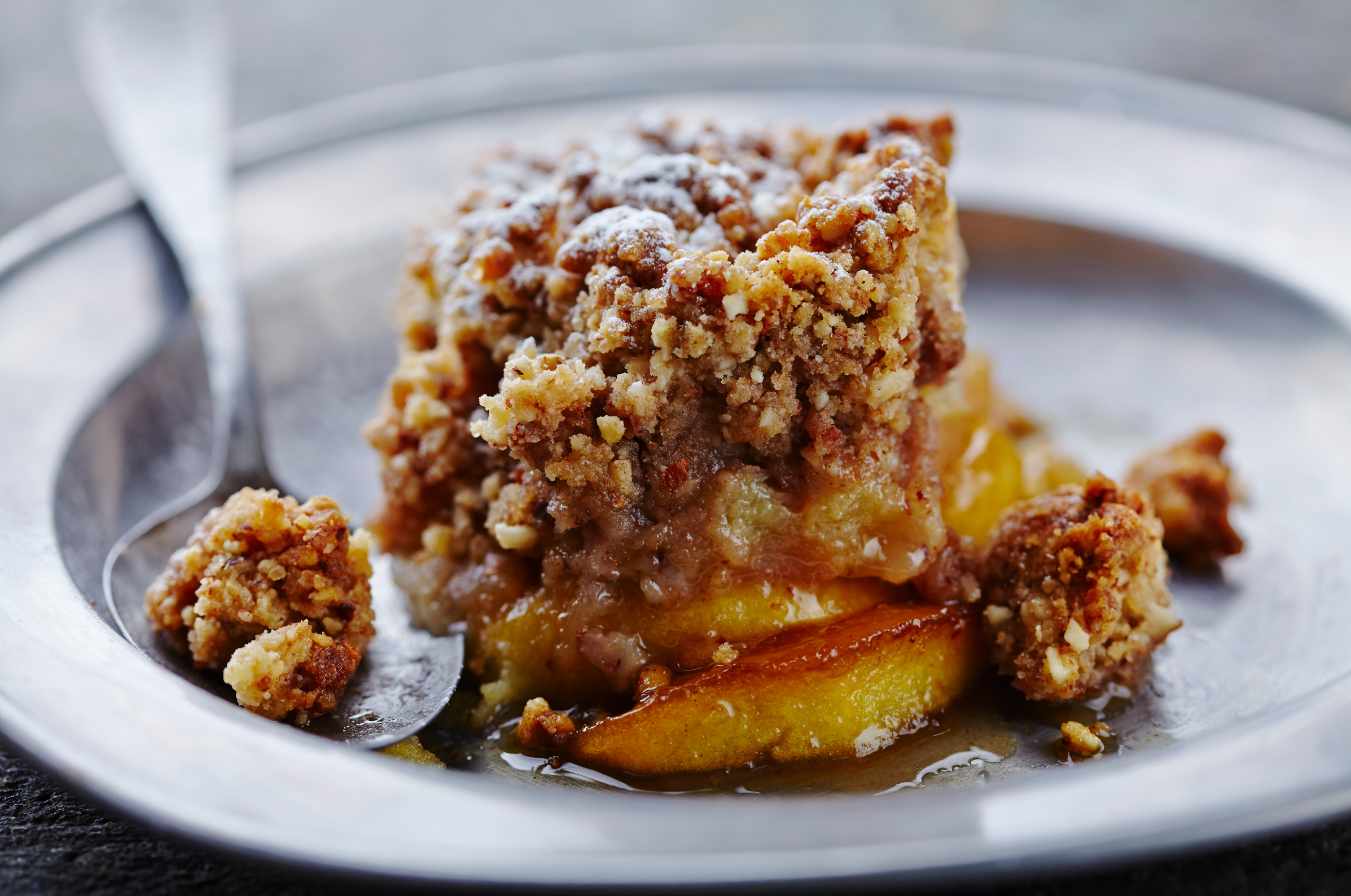 Image of Pro Chefly warm apple crumble with golden baked apples and a crisp nut topping served on a plate with a spoon in soft autumn lighting.
