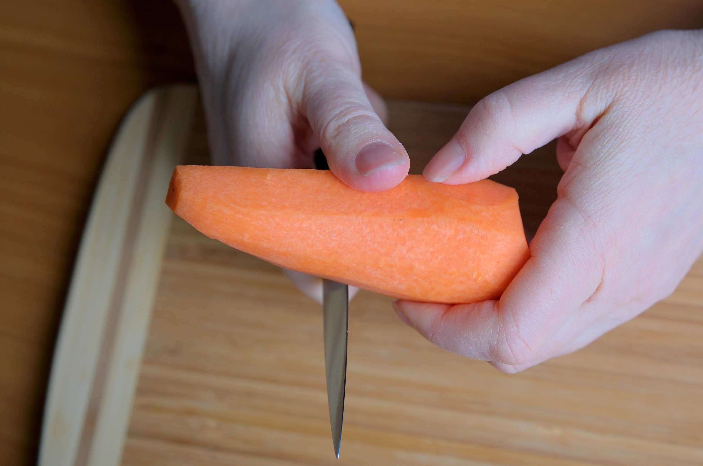 **Alt text:** Hands holding a carrot while cutting with a sharp Japanese knife.