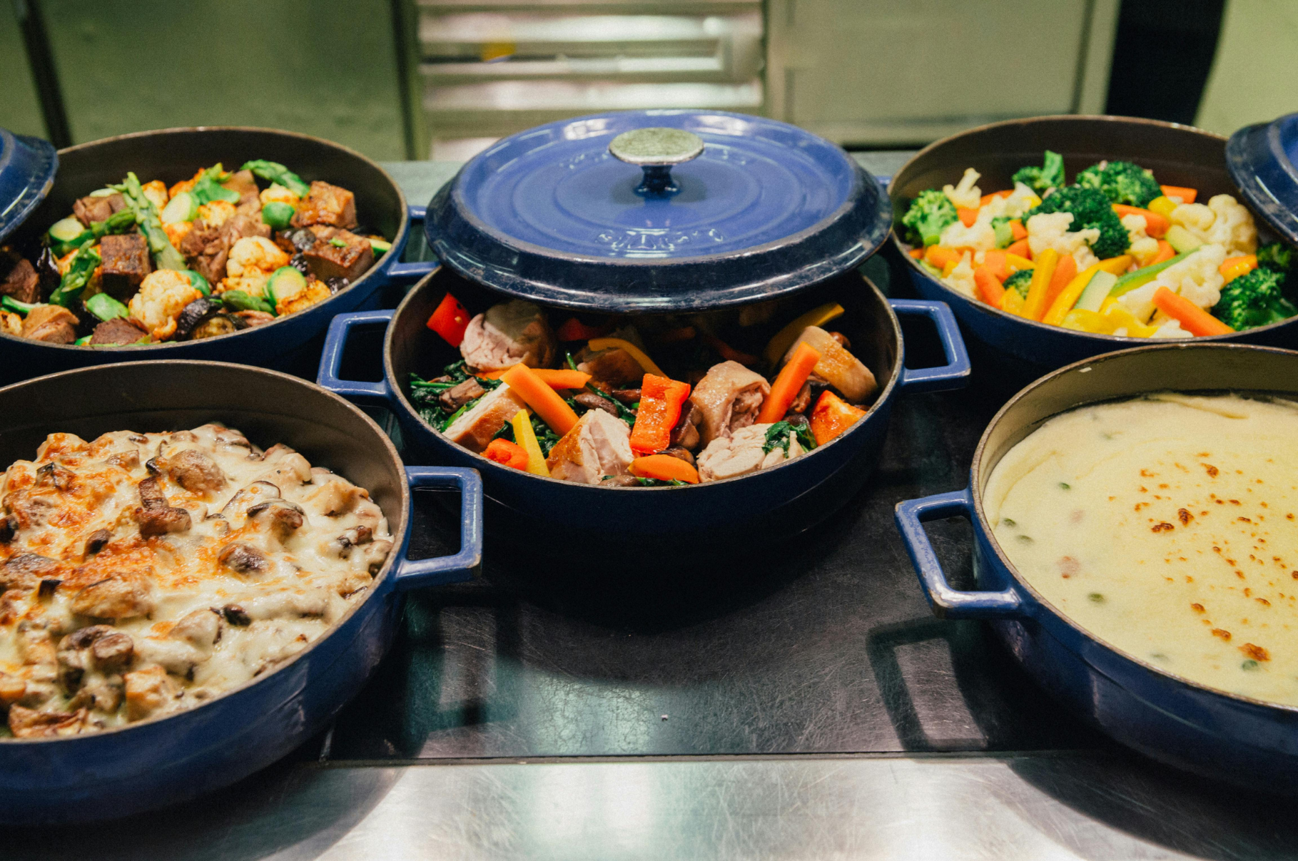 Colorful fall dishes simmering in blue cast iron pots, featuring roasted vegetables, creamy casseroles, and stews prepared with precision using Pro Chefly Japanese knives.