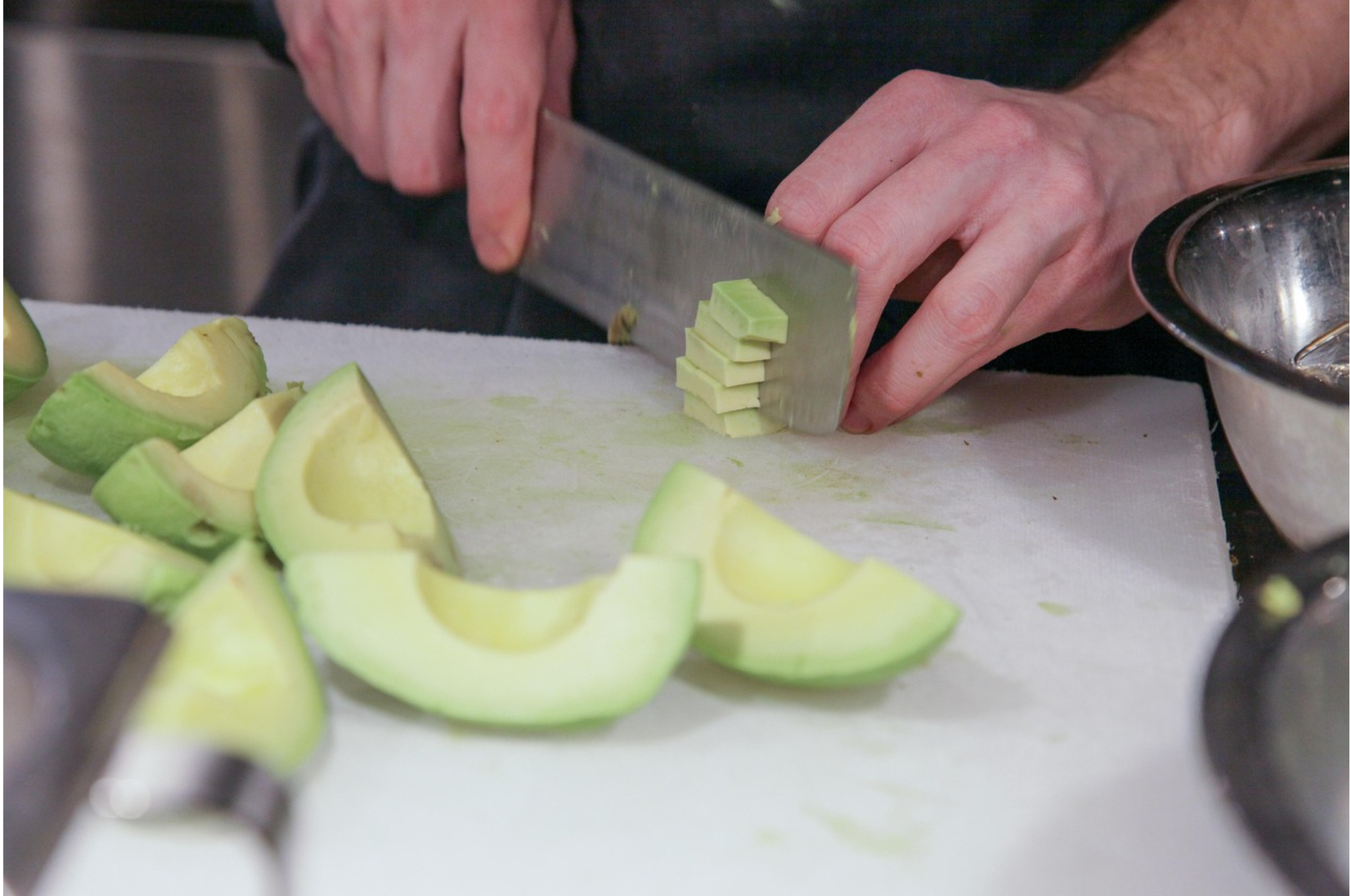 Chef slicing fresh avocado with a Damascus kitchen knife on a cutting board – Pro Chefly precision blades for everyday prep.