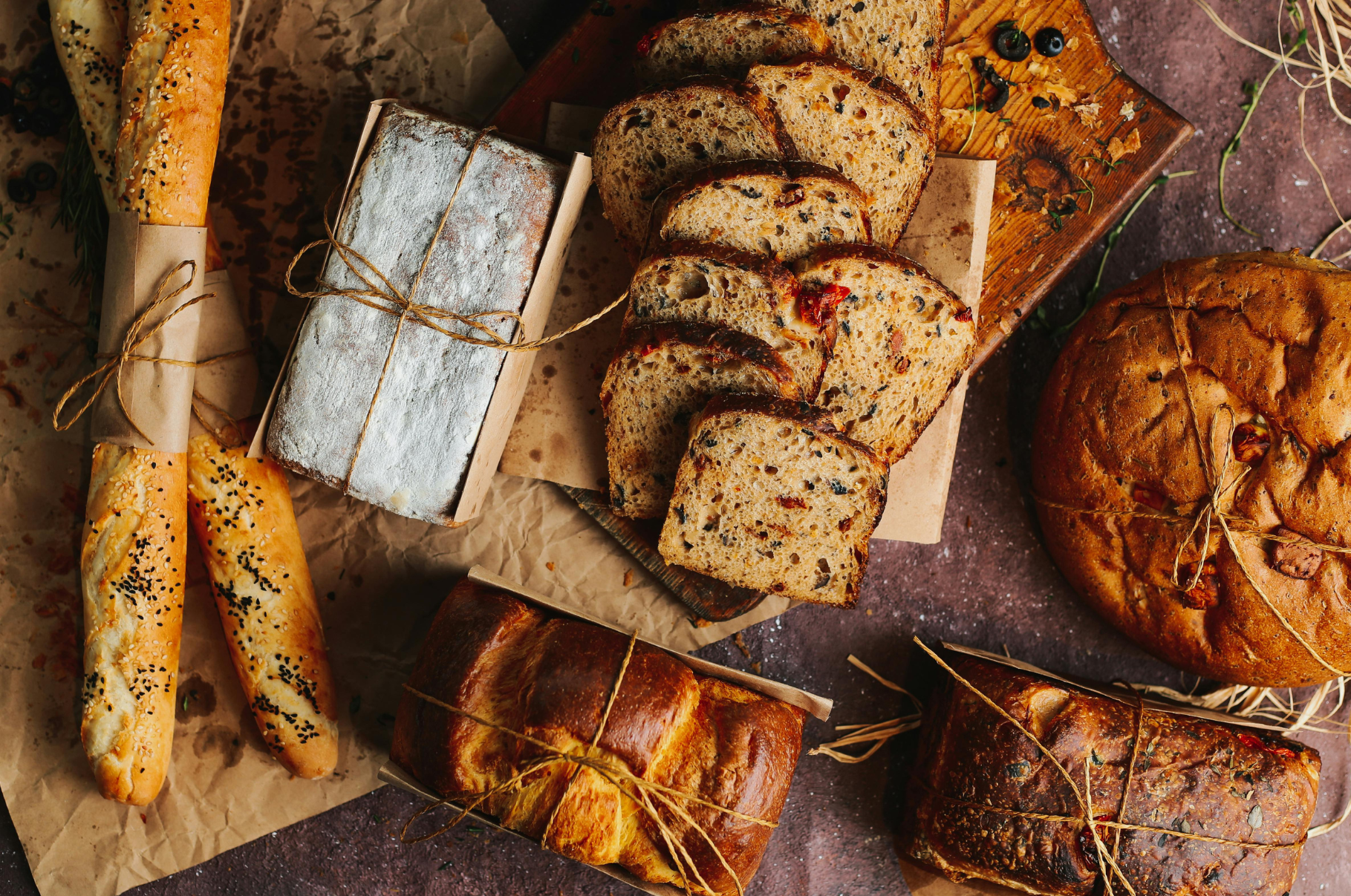 Image of Freshly baked artisan breads and loaves tied with rustic twine, showcasing texture and golden crust — a perfect scene for Pro Chefly’s bread-cutting precision and culinary craftsmanship.