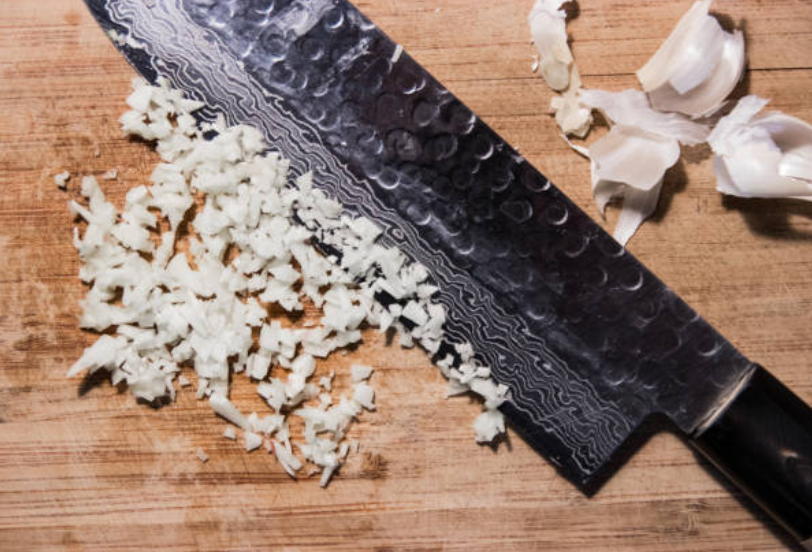 Image of Pro Chefly Damascus steel vs stainless steel knife comparison on wooden cutting board