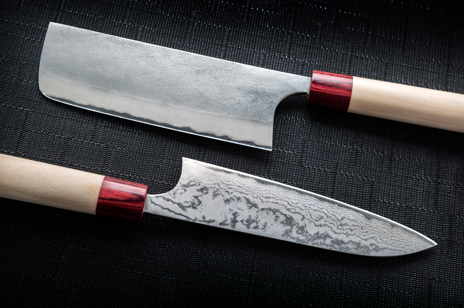 Close-up of Japanese Damascus steel knives with wooden handles and intricate wave patterns – Pro Chefly premium cutlery
