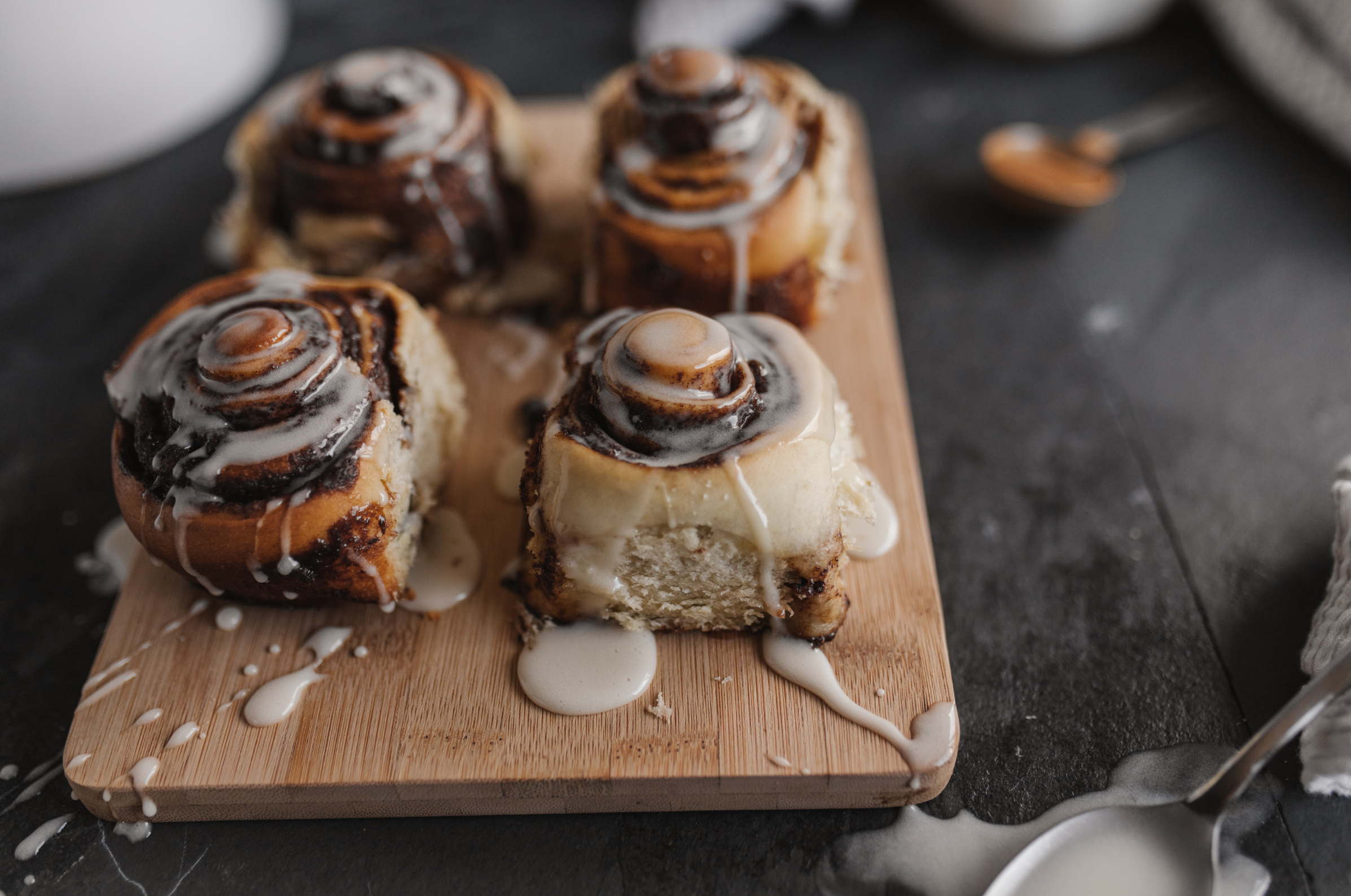 Image of pro chefly cinnamon rolls with vanilla glaze on wooden board, showcasing artisanal baking and handcrafted presentation