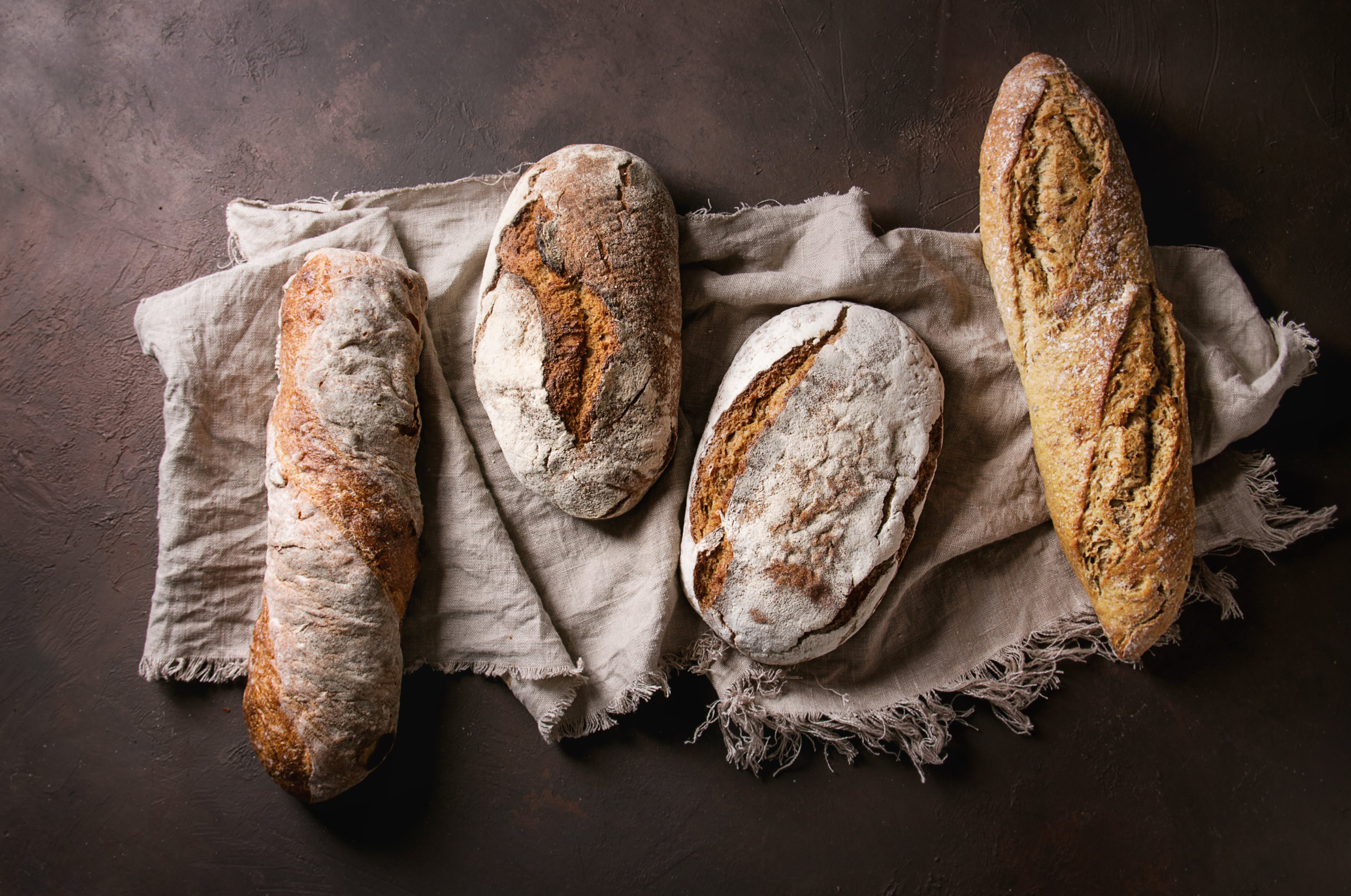 pro chefly artisan bread loaves on linen cloth, highlighting rustic texture and handcrafted baking artistry