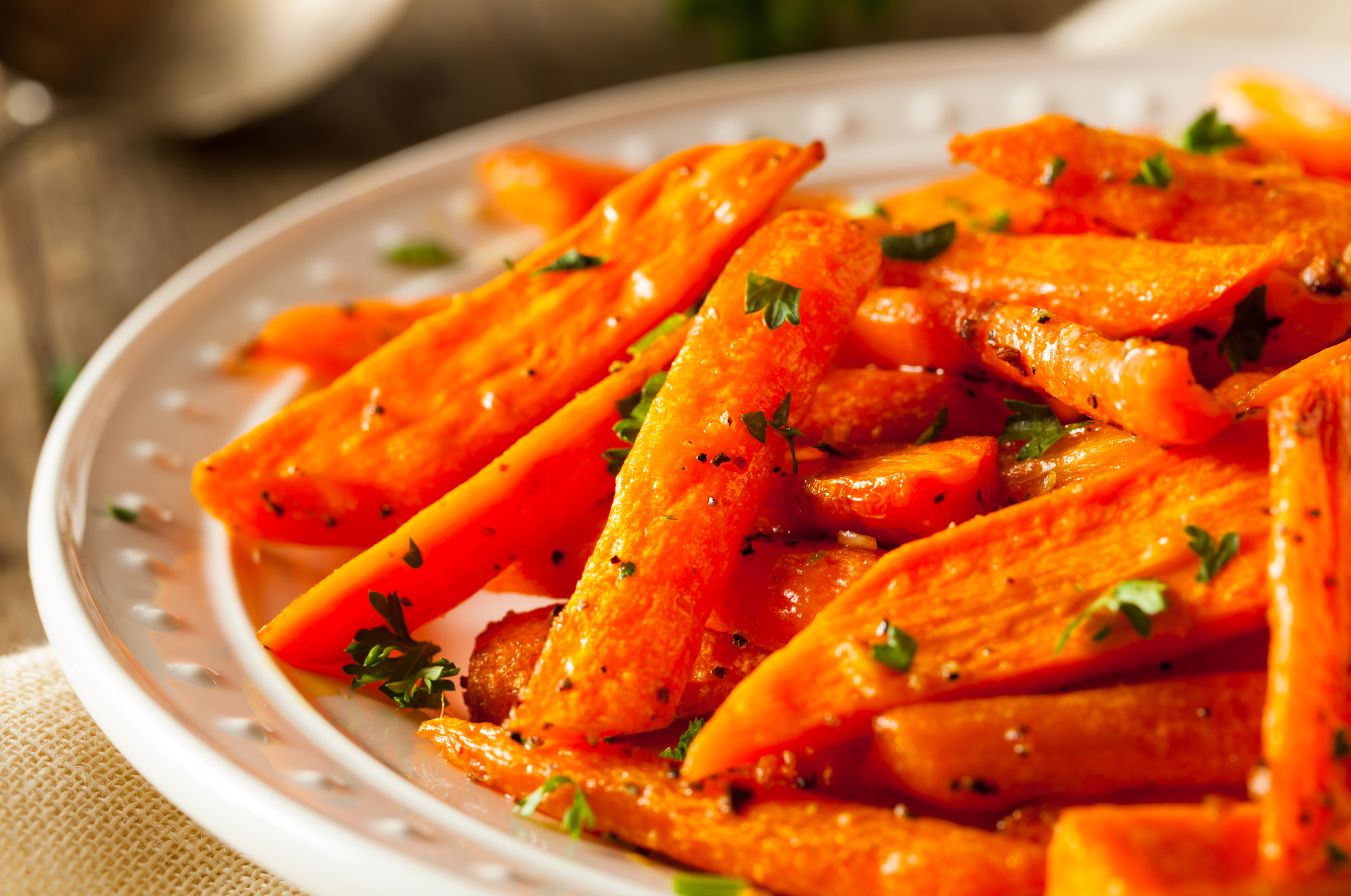 **Alt text:** Honey roasted carrots garnished with fresh herbs on a white plate.