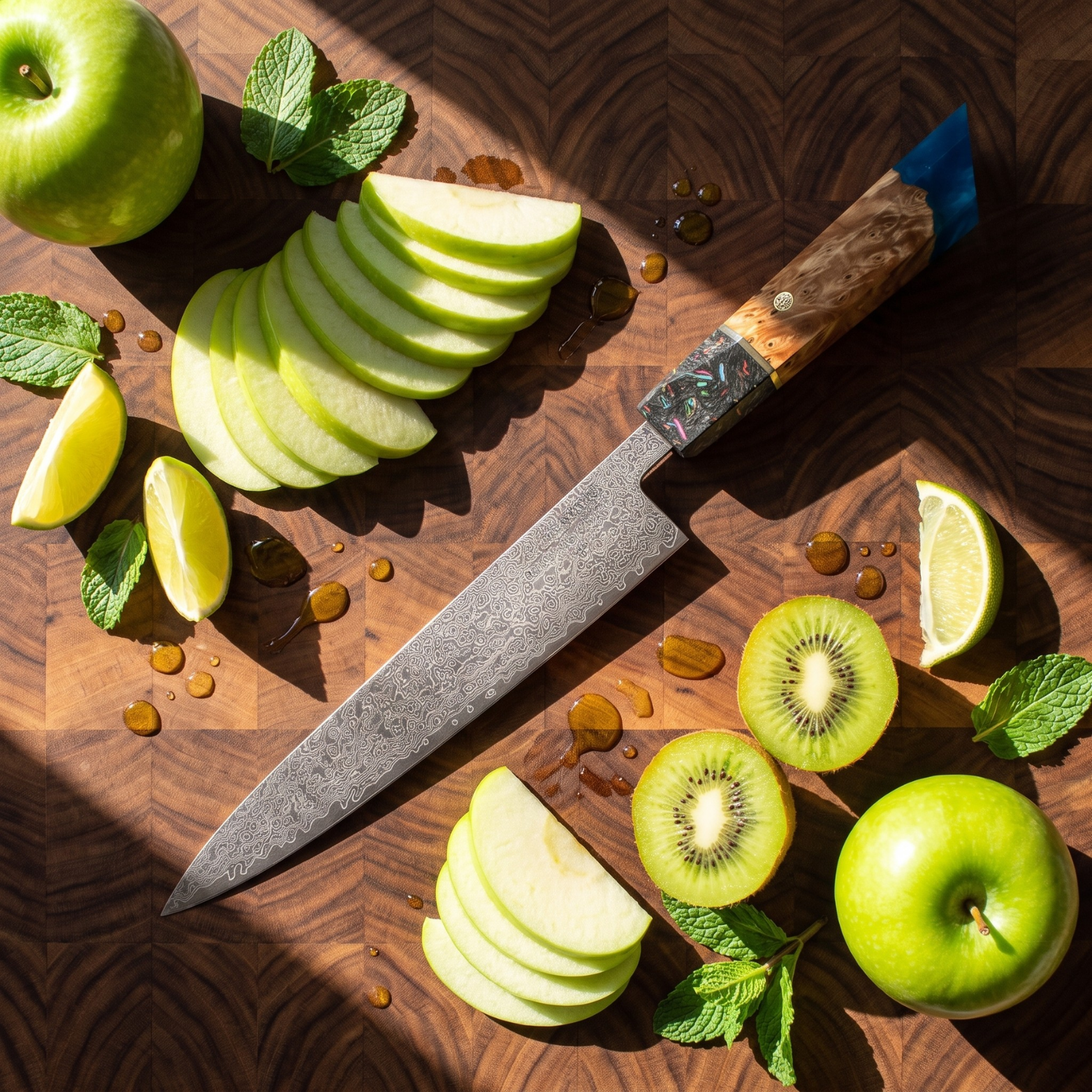 Image of Pro Chefly 8-inch Damascus chef knife with blue burl resin handle, overhead with fanned green apple, kiwi and lime