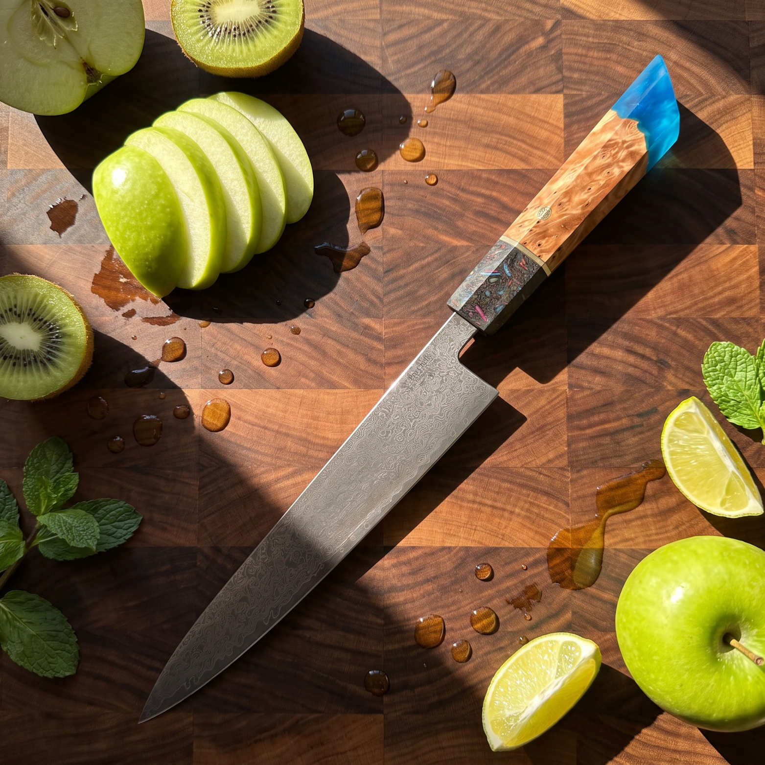 Image of Pro Chefly 8-inch Damascus chef knife with blue burl resin handle, overhead on an end-grain board with apple, kiwi and lime