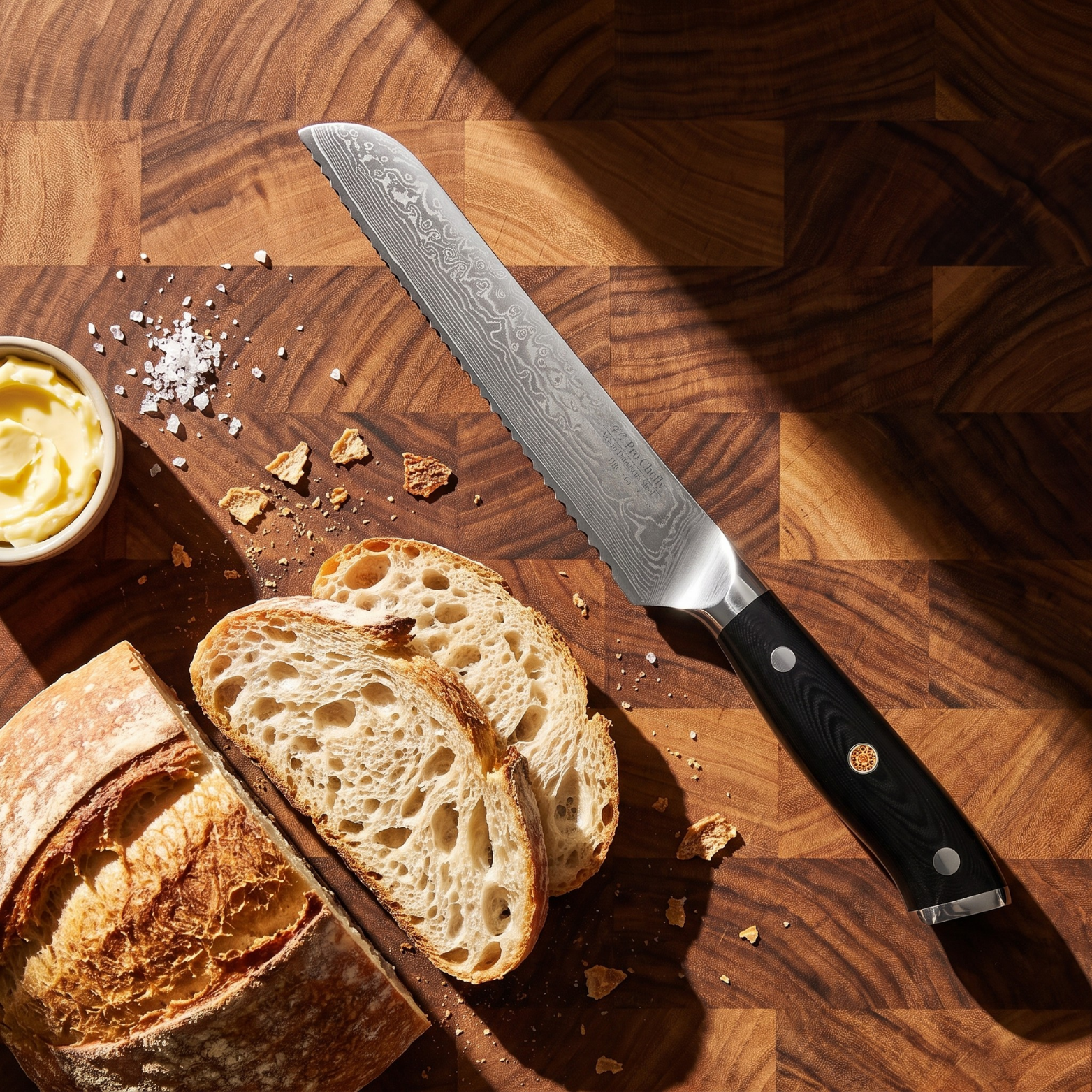 Image of Pro Chefly 8-inch Damascus bread knife with black triple-riveted handle, overhead on an end-grain board with sourdough, butter and salt