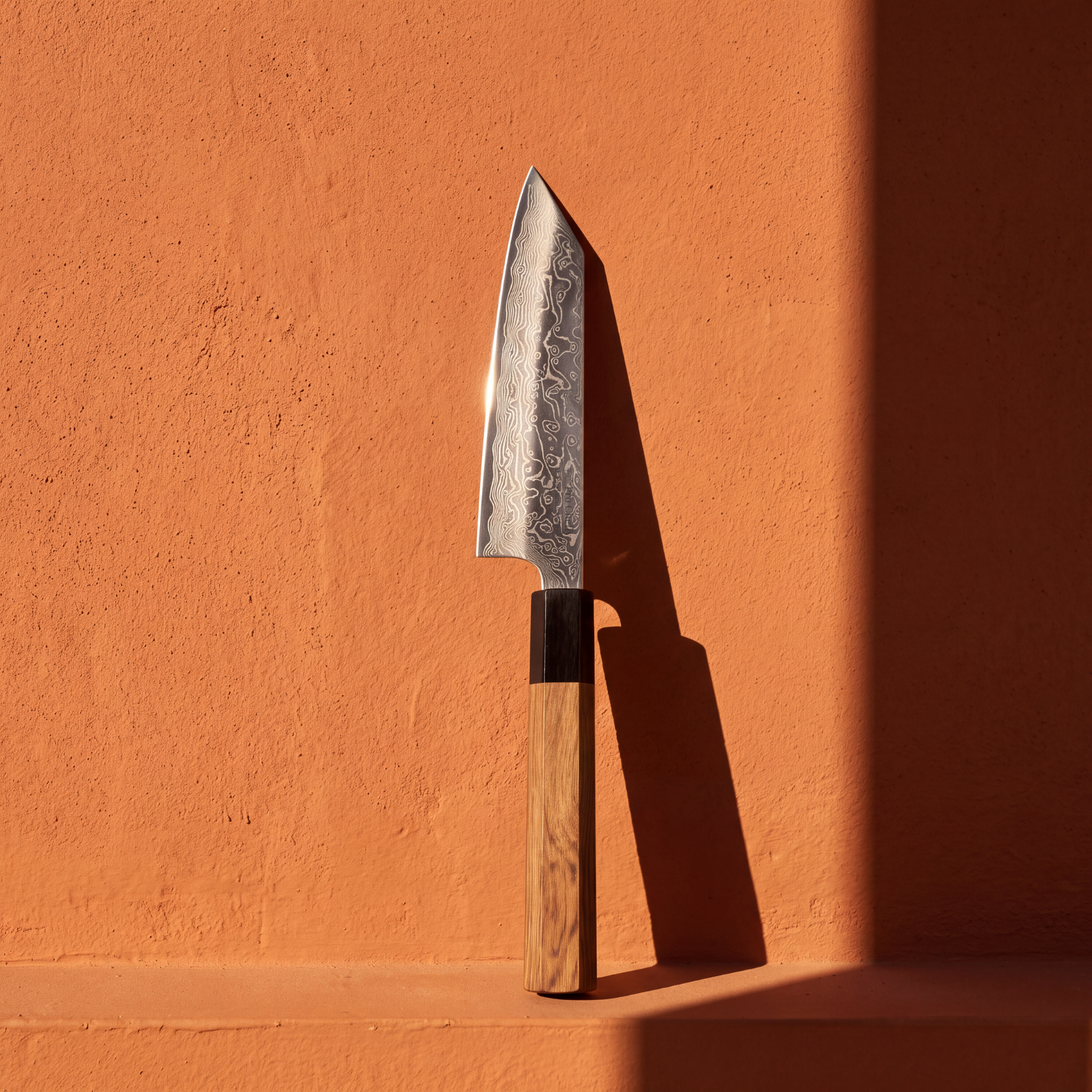 Pro Chefly 5-inch Damascus mini bunka knife with olivewood wa handle, standing against a terracotta wall