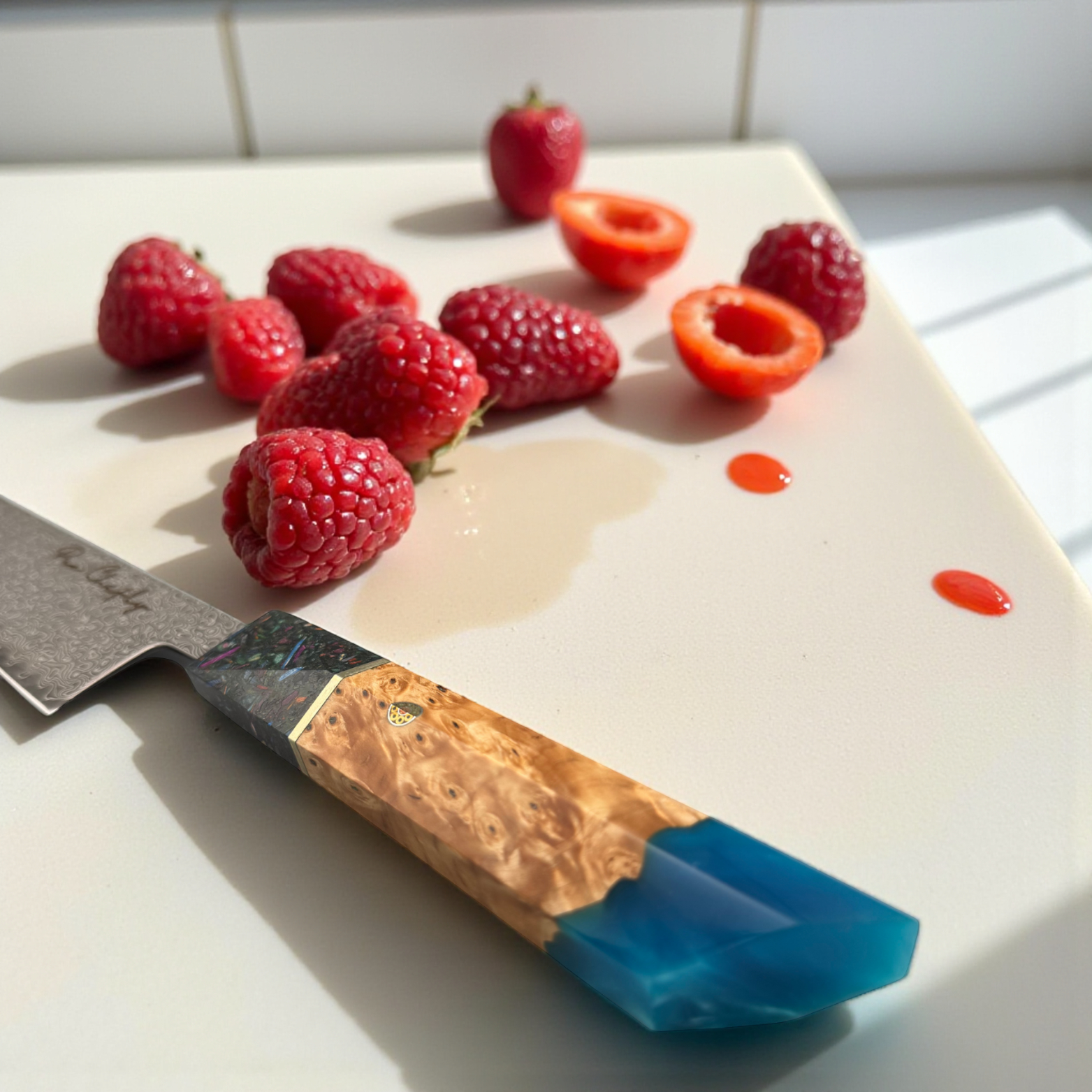 Image of Pro Chefly AUS-10 Damascus steel Japanese gyuto knife with resin and wood handle on cutting board beside raspberries and sliced strawberries.