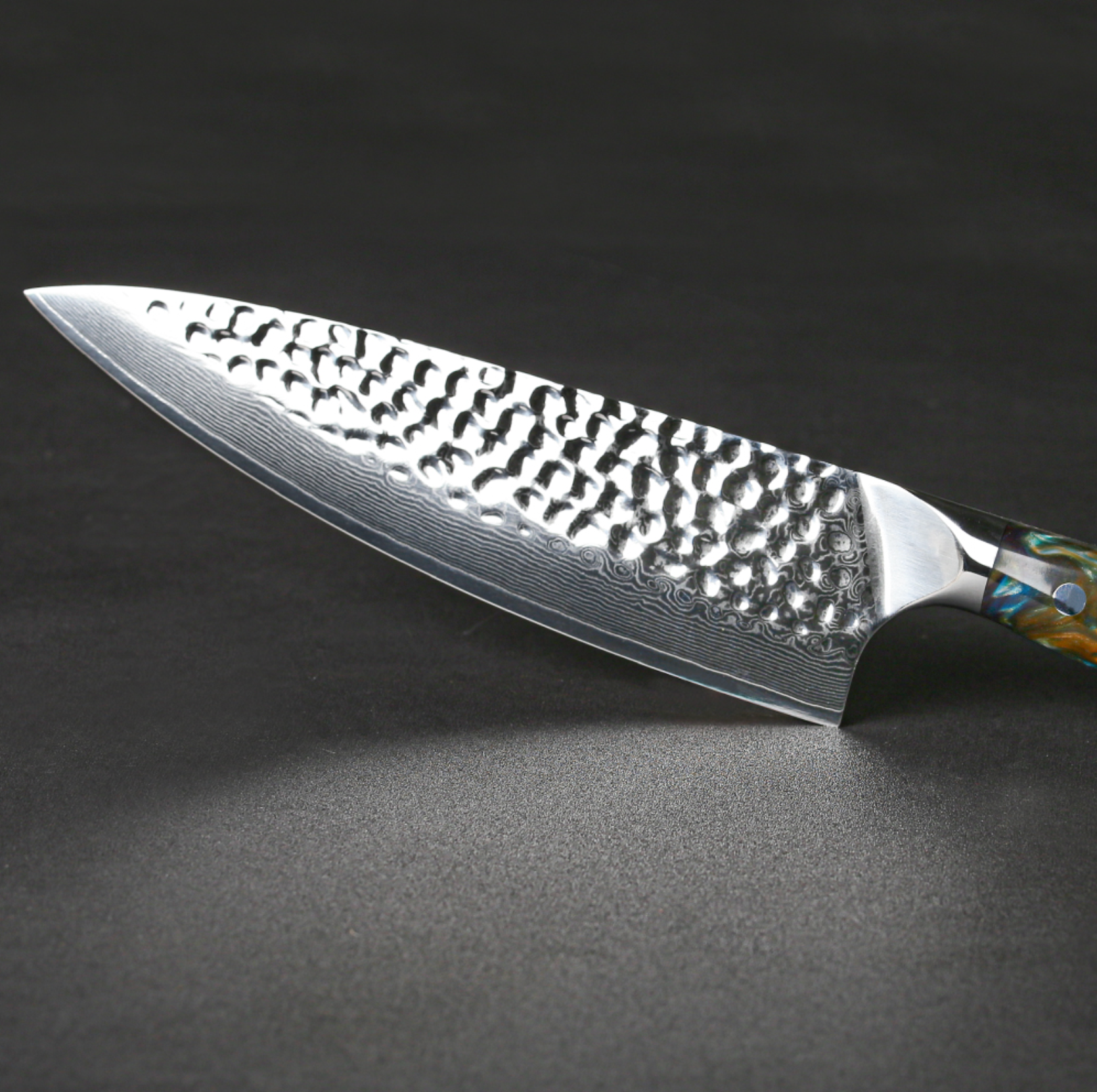 Image of Pro Chefly VG-10 Damascus steel Japanese chef knife with resin handle and hammered Damascus blade displayed diagonally on dark surface.